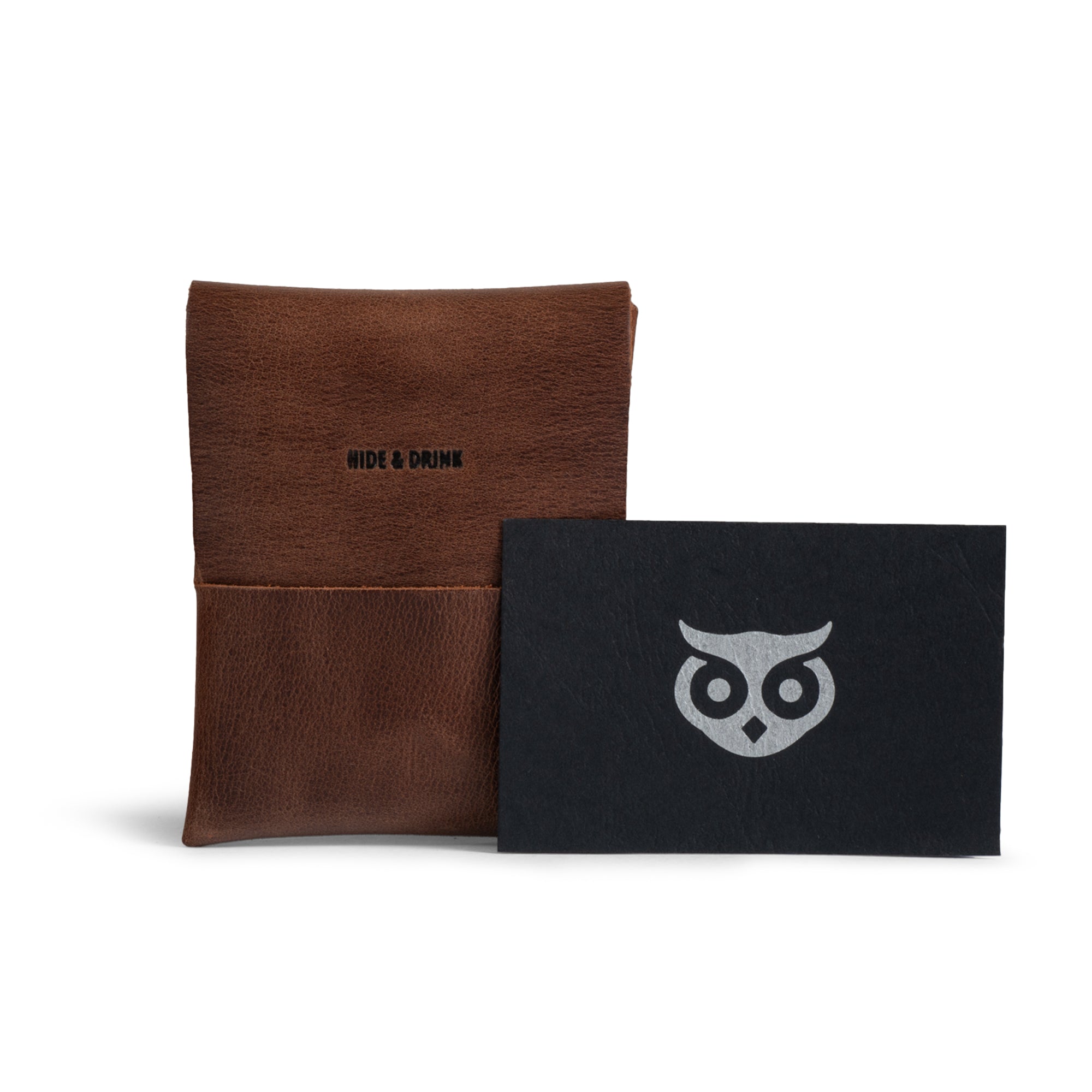 The Origami Card Wallet by Hide & Drink displayed alongside a branded card, emphasizing its unique craftsmanship and story. This Leather Origami Card Holder functions well as a Slim Wallet for Cards and Front Pocket Case for Debit & Credit Cards. Hand Cut and Hand Sewn in La Antigua Guatemala & Oaxaca Mexico, it's a great representation of quality artisan products.