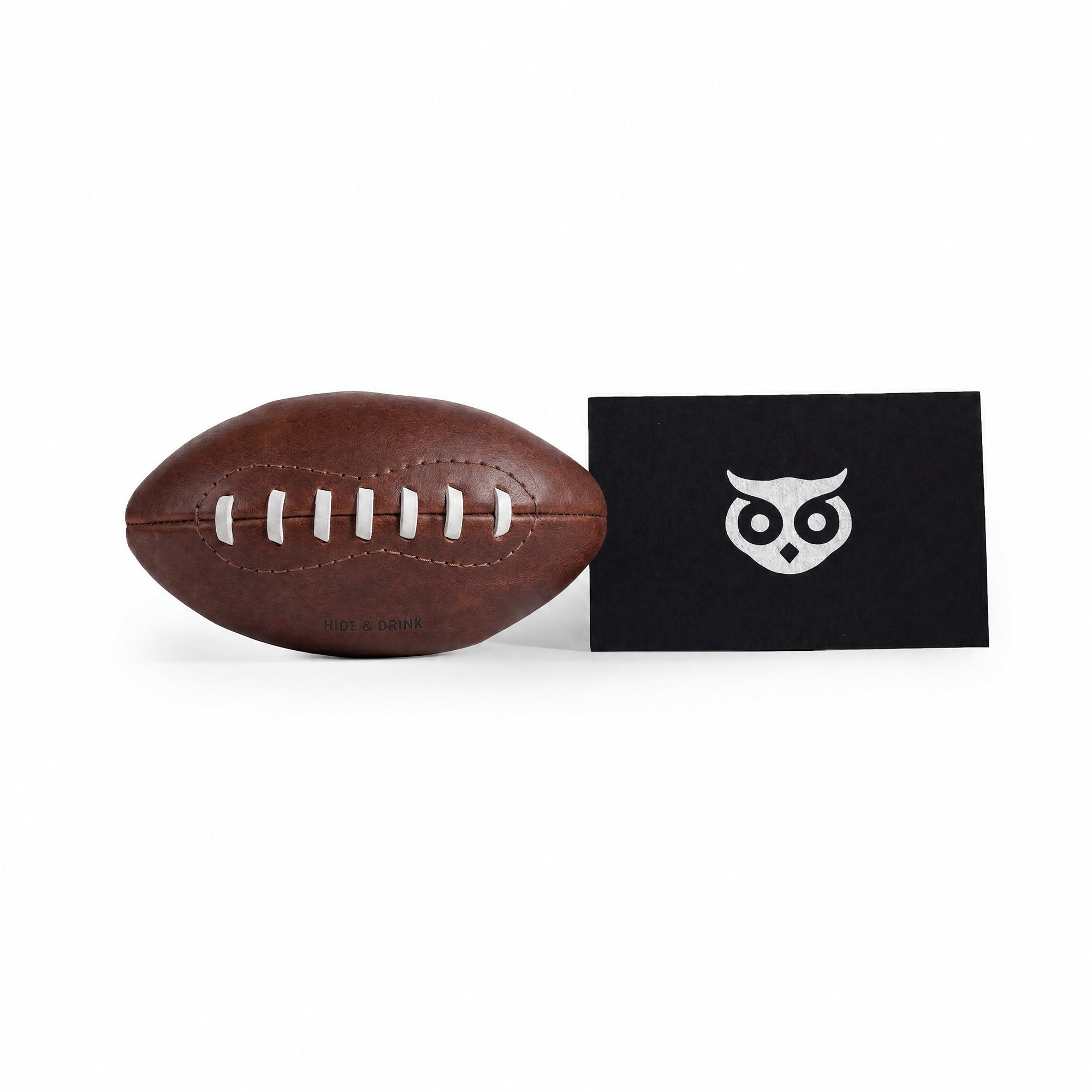 Mini American Football by Hide & Drink along with care cards showcasing its artisan heritage. This hand stitched ball is made from full grain leather, perfect as a keepsake or decorative piece, highlighting the unique craftsmanship from La Antigua Guatemala & Oaxaca Mexico.