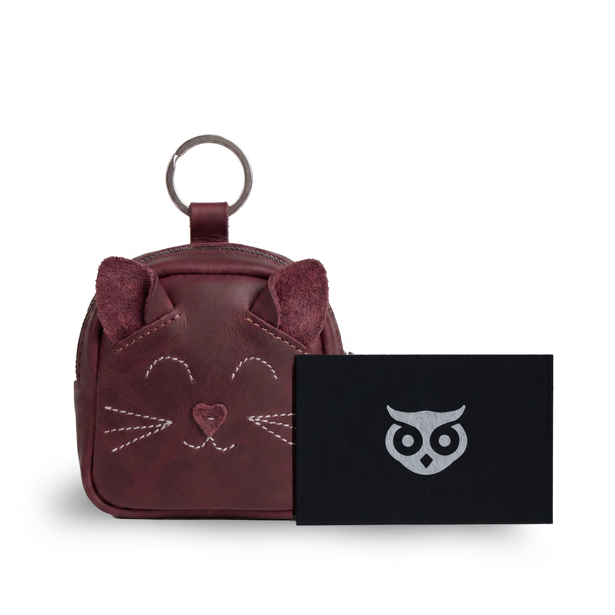 The Cheery Cat Mini Pack from Hide & Drink is presented with a branding card, showcasing its quality as a gift option. This charming coin purse made from Full Grain Leather highlights artisan production from La Antigua Guatemala & Oaxaca, Mexico, perfect for any animal lover.