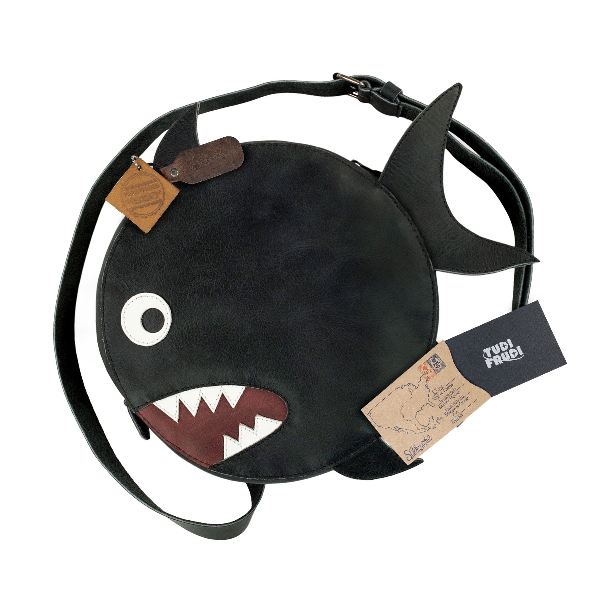 Features of Tudi Frudi's Piranha-Shaped Shoulder Bag are showcased with stylish tags for authenticity and heritage. This Piranha-Shaped Circular Shoulder Bag, crafted from Full Grain Leather, represents the essence of handmade artisan craftsmanship from La Antigua, Guatemala, perfect for those seeking a unique, playful touch in their accessories.
