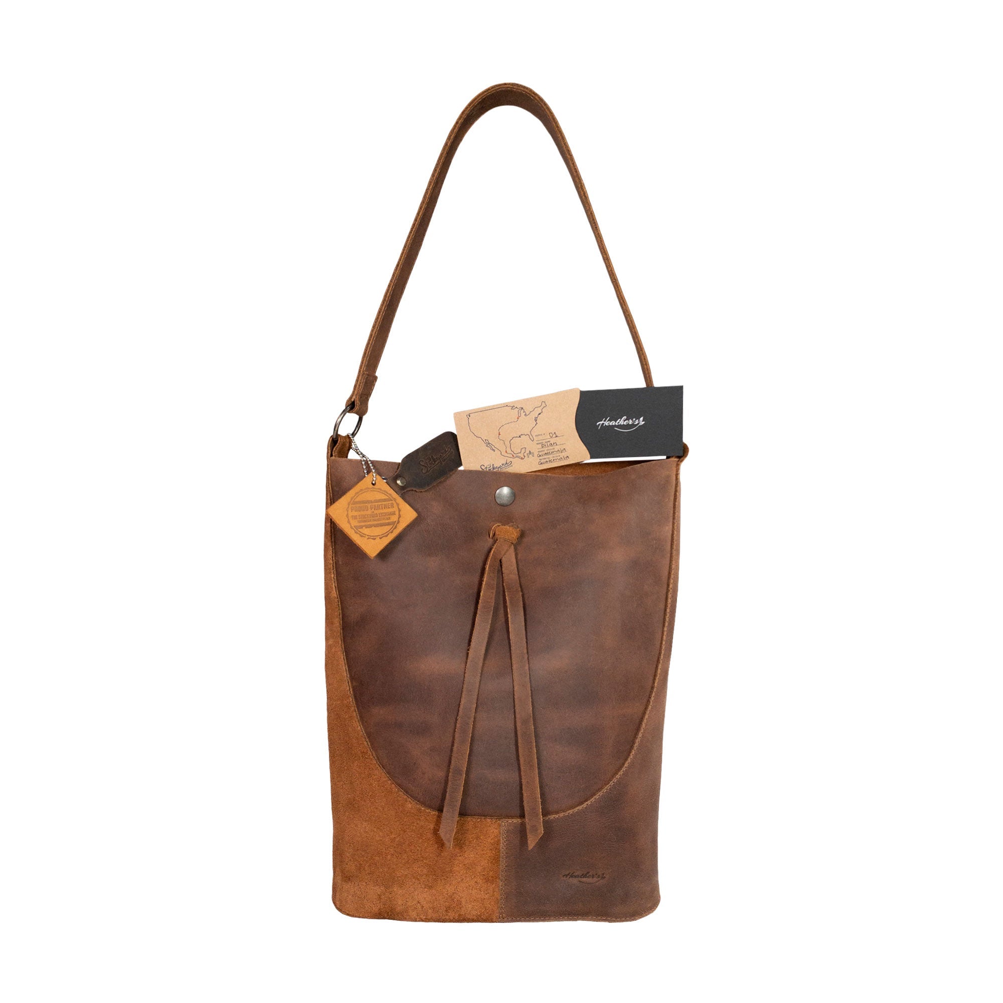 Heather's Reversed Shoulder Bag displayed with a tag indicating artisan craftsmanship, emphasizing its quality. This rustic tote bag for women serves as a stylish vintage purse and shoulder bag with strap, created from full grain leather in small batches by artisans in La Antigua Guatemala & Oaxaca Mexico.