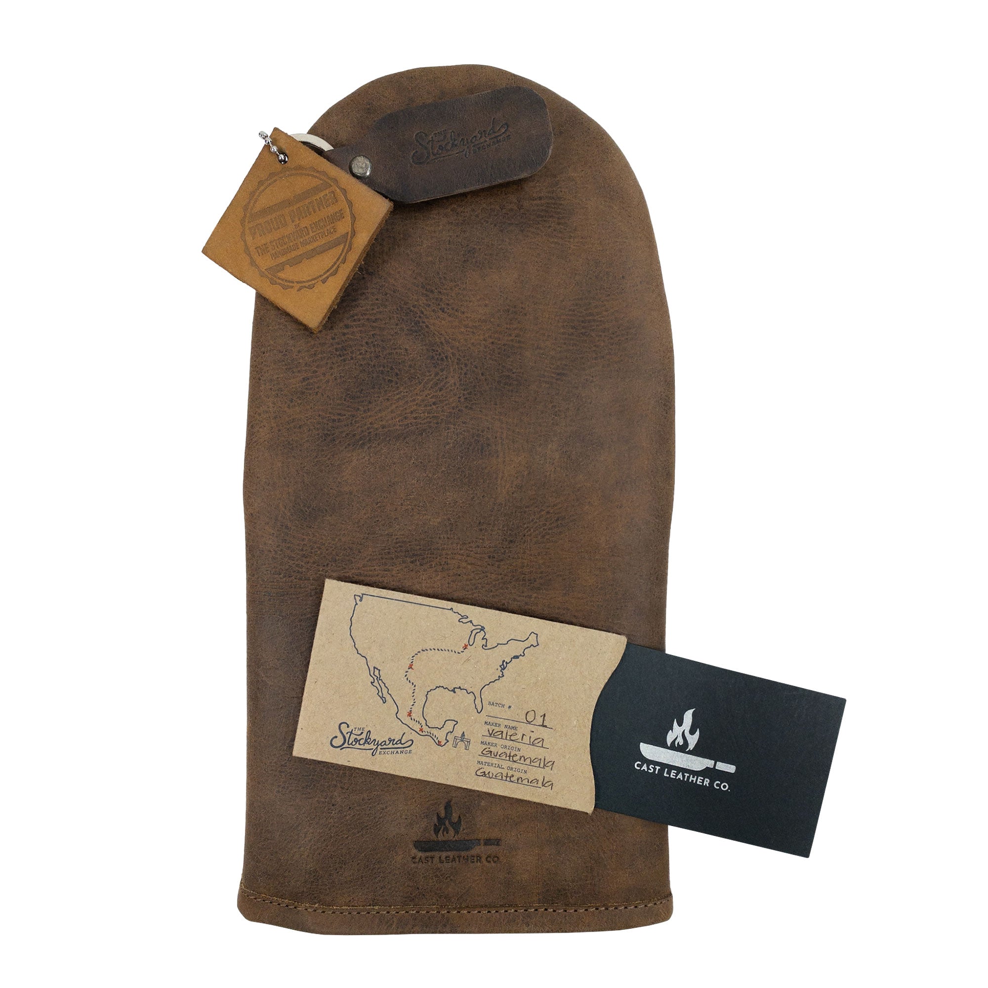The Cast Leather Co. Oven Mitt Heat Resistant presented with care instructions attached. This Single Oven Mitt Glove Heat Resistant serves as a functional potholder in the kitchen, crafted from high-quality full grain leather. The StockyardX product exemplifies small batch production, with meticulous hand cut and hand sewn techniques, supporting artisan craftsmanship from La Antigua Guatemala & Oaxaca Mexico.