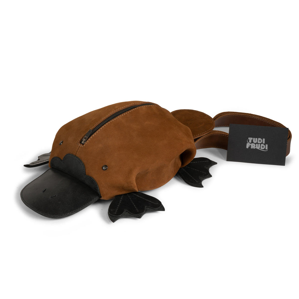 Tudi Frudi Platypurse Crossbody Bag displayed with branded packaging, highlighting the brown Swayze Suede and Full Grain Leather platypus design, Adjustable Shoulder Strap, Messenger Bag and Shoulder Bag styling, Zippered Sling Bags function, Travel Backpack versatility, Purses for Men and Women appeal, Satchel shape, StockyardX Small Batch Production, Hand Cut and Hand Sewn Artisan craftsmanship, Fire Branded detail, Handmade in La Antigua Guatemala & Oaxaca Mexico.