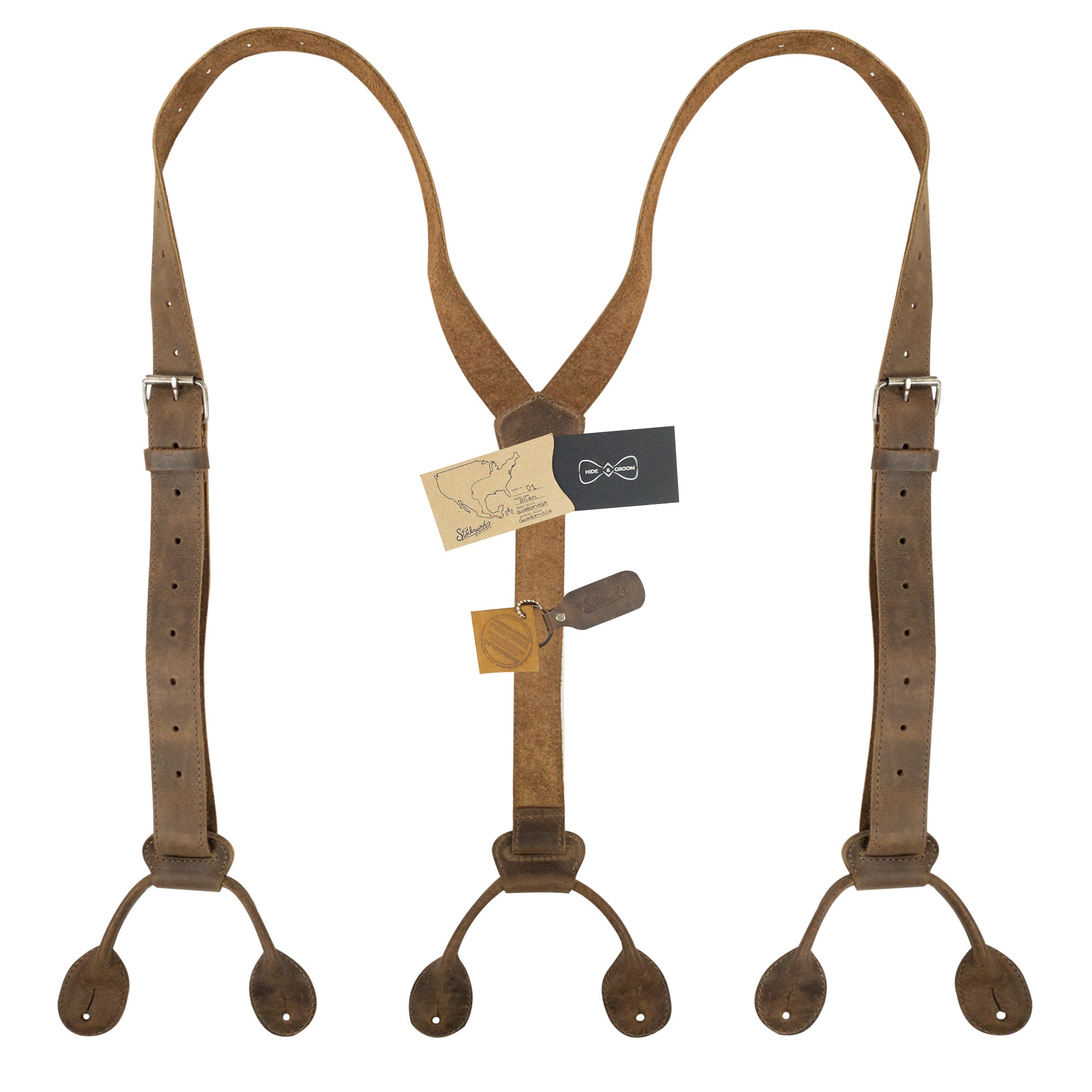 Y Back Button End Suspenders by Hide & Groom, displayed with tags showcasing their artisan craftsmanship. These suspenders are perfect for groomsmen and versatile for any formal event. Made from durable full grain leather, each piece is hand cut and sewn, representing the quality of small batch production from Guatemala.