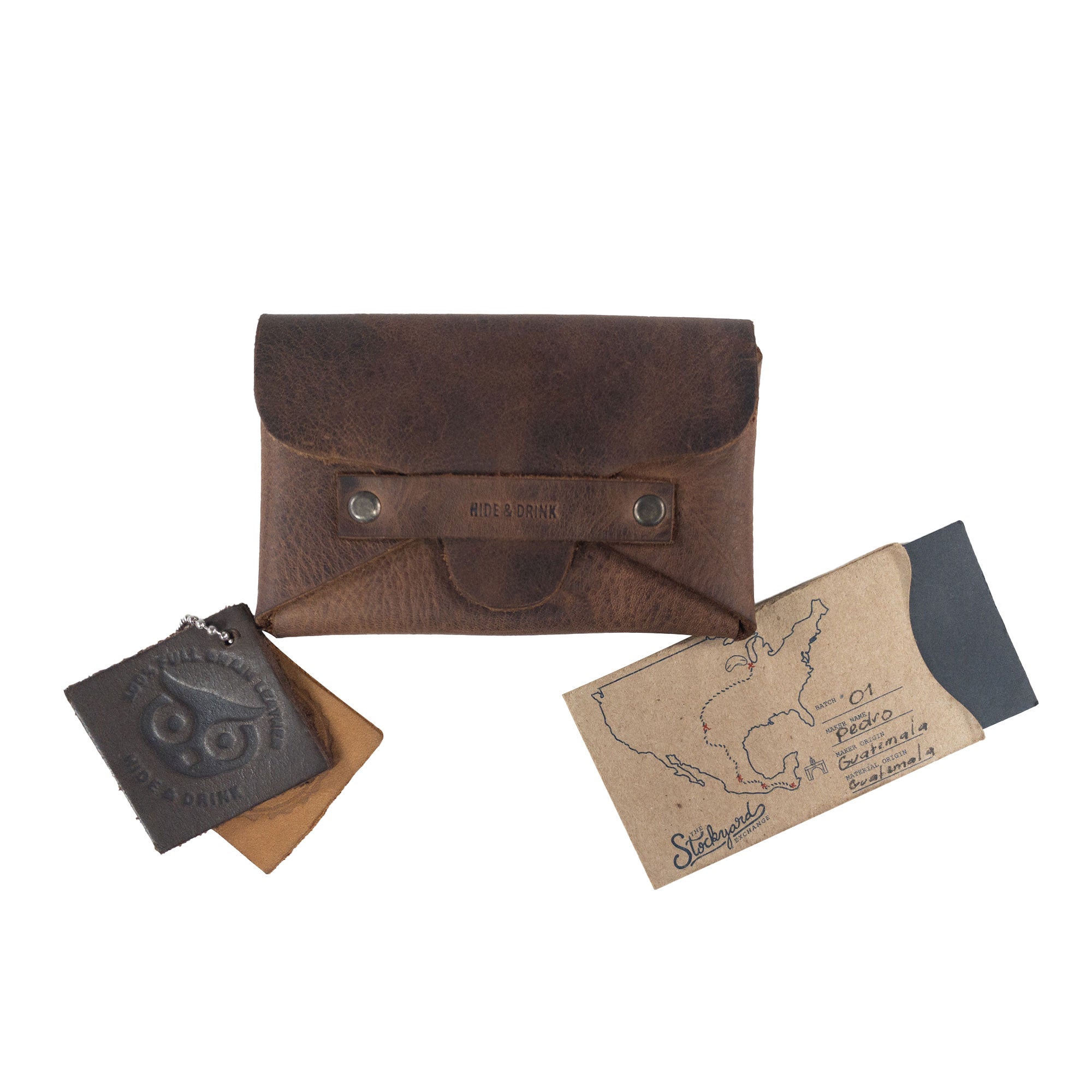 Hide & Drink's Snapless Business Card Holder alongside leather samples and packaging showcasing artisan craftsmanship. This vintage wallet is a sturdy pouch that organizes cards and cash effectively. Made from Full Grain Leather, it exemplifies StockyardX’s dedication to small batch production, emphasizing hand cut and hand sewn techniques by artisans in La Antigua Guatemala and Oaxaca Mexico.