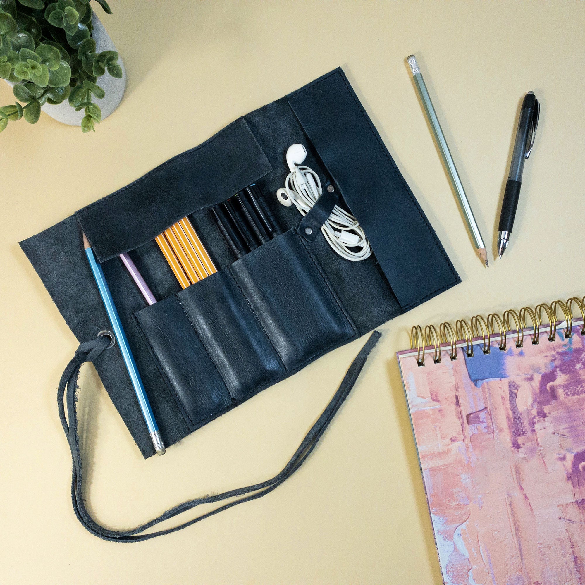 Detailed view of the Hide & Drink Multi Purpose Pencil Roll, displaying its storage versatility for art and work items. The rustic leather finish highlights the handmade quality and craftsmanship from La Antigua Guatemala & Oaxaca Mexico.