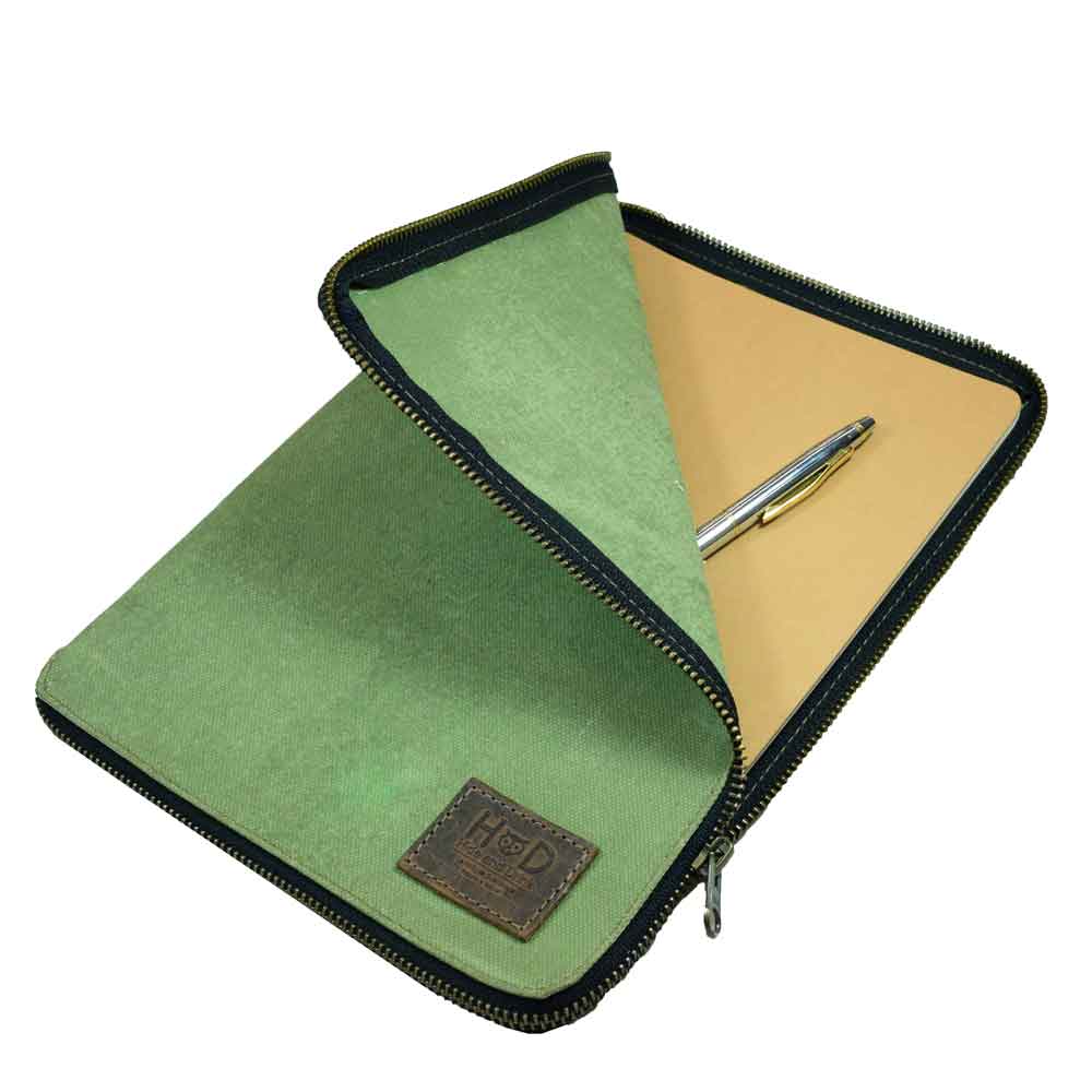 Open view of the Waxed Canvas Zippered Journal Cover for Moleskine (Notebook NOT Included) by Hide & Drink featuring a pen and beautifully crafted interior, perfect for Cahier Cases and notes. Made from durable Full Grain Leather with artisan care in La Antigua Guatemala & Oaxaca Mexico.