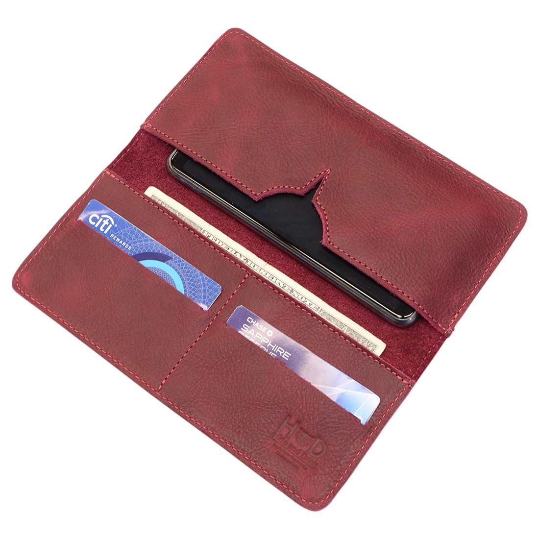 Open red bifold wallet for cellphone by Hide & Drink, showcasing card and cash compartments. This stylish Bifold Wallet for Cellphone is made from high-quality Full Grain Leather, perfect for effortless organization. Enjoy artisan craftsmanship with this handmade piece, produced in small batches in La Antigua Guatemala & Oaxaca Mexico.