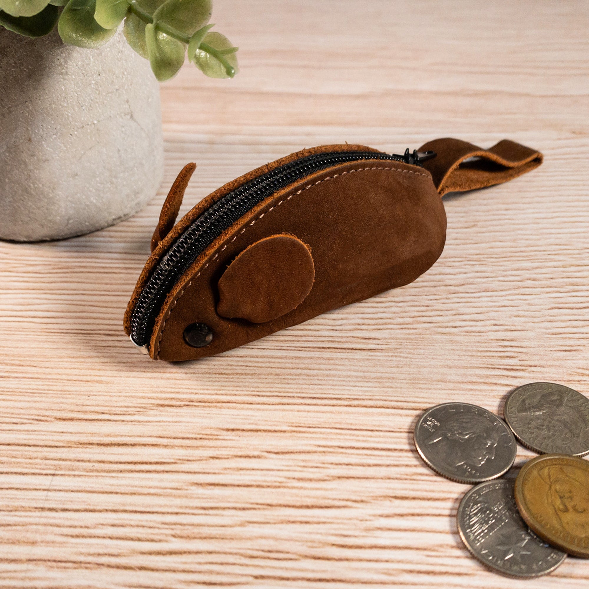 Hide & Drink Mouse Coin Pouch on a wooden table, emphasizing its cute and functional design. This Mouse-Shaped Coin Pouch is not just a Change Pouch but also a perfect Pocket Case for Coins and Travel Accessory, made from rich Full Grain Leather.