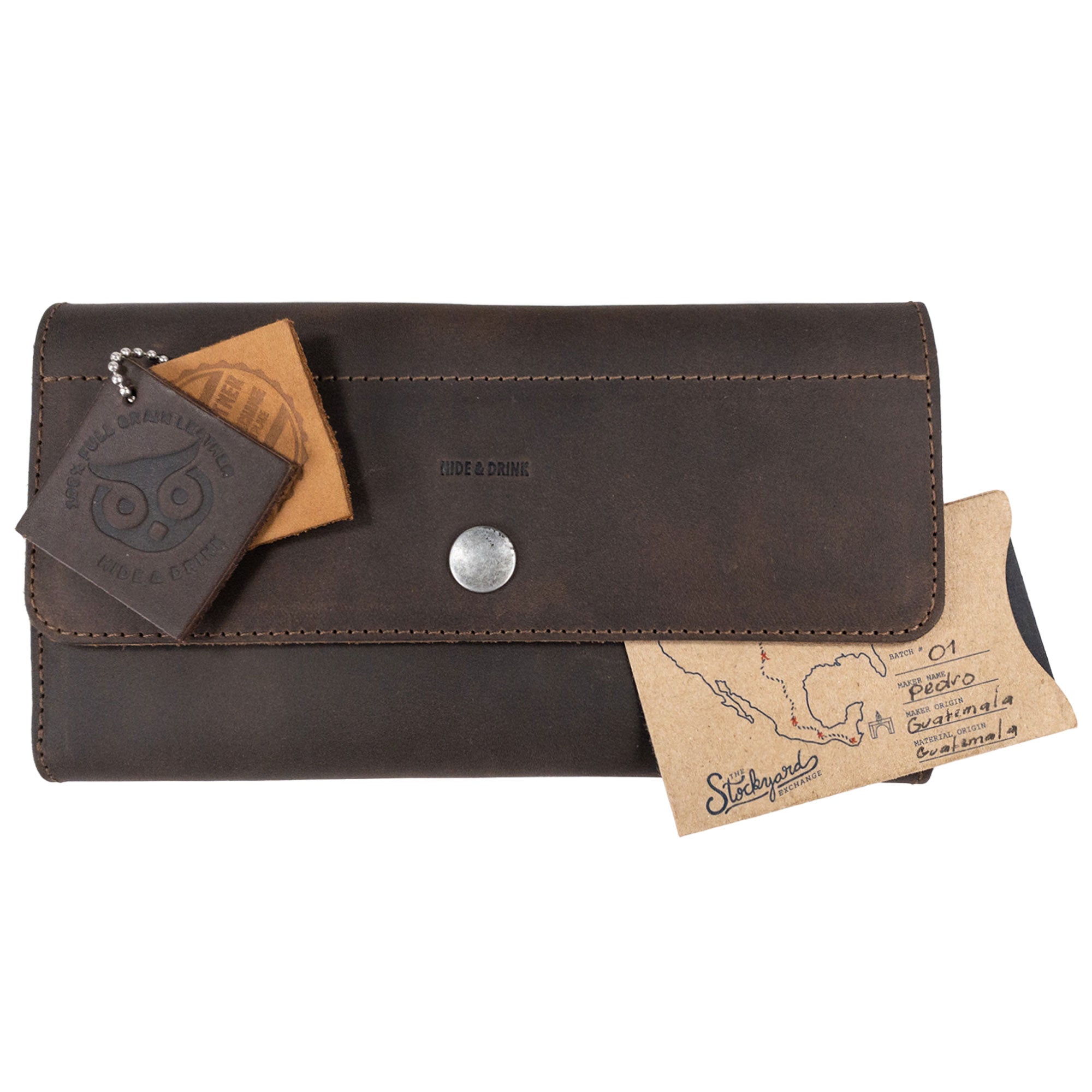 The Rustic Tri Fold Folio Wallet by Hide & Drink displayed with tags, emphasizing its unique character and artisan quality. This wallet is the ideal Minimalist Tri Fold Folio Wallet for Women, made from full grain leather with an emphasis on small batch production, showcasing hand cut and hand sewn craftsmanship, proudly handmade in La Antigua Guatemala & Oaxaca Mexico.