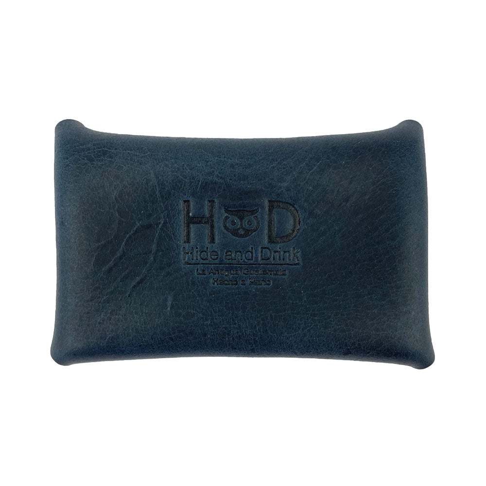 The navy Hide & Drink Envelope Coin Case displaying the brand's logo, emphasizing quality craftsmanship. This full grain leather case is handmade in La Antigua Guatemala & Oaxaca Mexico, merging style with functionality.