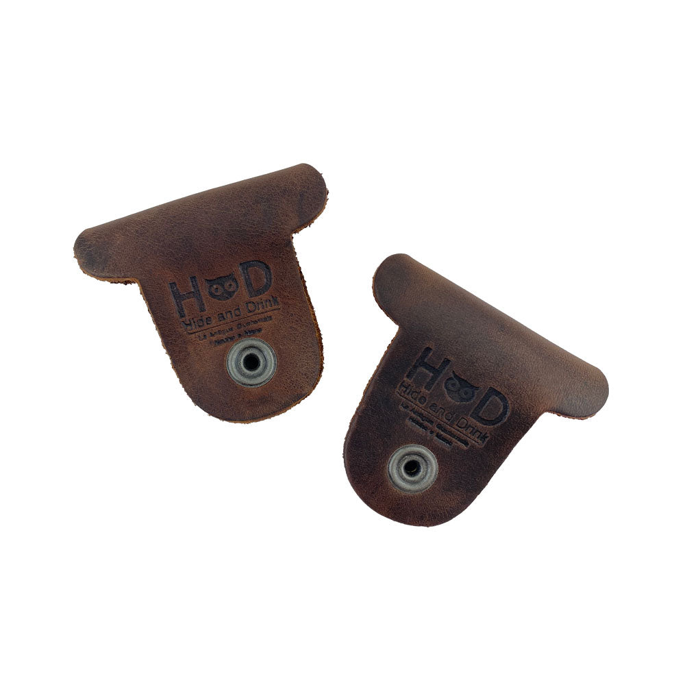 Two dark brown Dog Shaped Cord Keepers with Hide & Drink branding, showcasing their craftsmanship in Full Grain Leather cord organization. Dog Shaped Cord Keeper (Cord Clam) 2-Pack, Full Grain Leather, StockyardX, Small Batch Production, Hand Cut, Hand Sewn, Fire Branded, Artisan, Handmade in La Antigua Guatemala & Oaxaca Mexico.