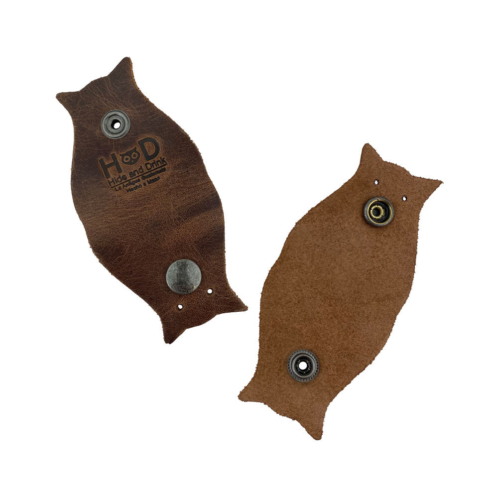 Stylish and Functional Owl Shaped Cord Keeper (2-Pack) by Hide & Drink emphasizing its design and usage with a focus on quality leather. Owl Shaped Cord Keeper (Cord Clam) 2-Pack. Full Grain Leather, StockyardX, Small Batch Production, Hand Cut, Hand Sewn, Fire Branded, Artisan, Handmade in La Antigua Guatemala & Oaxaca Mexico.