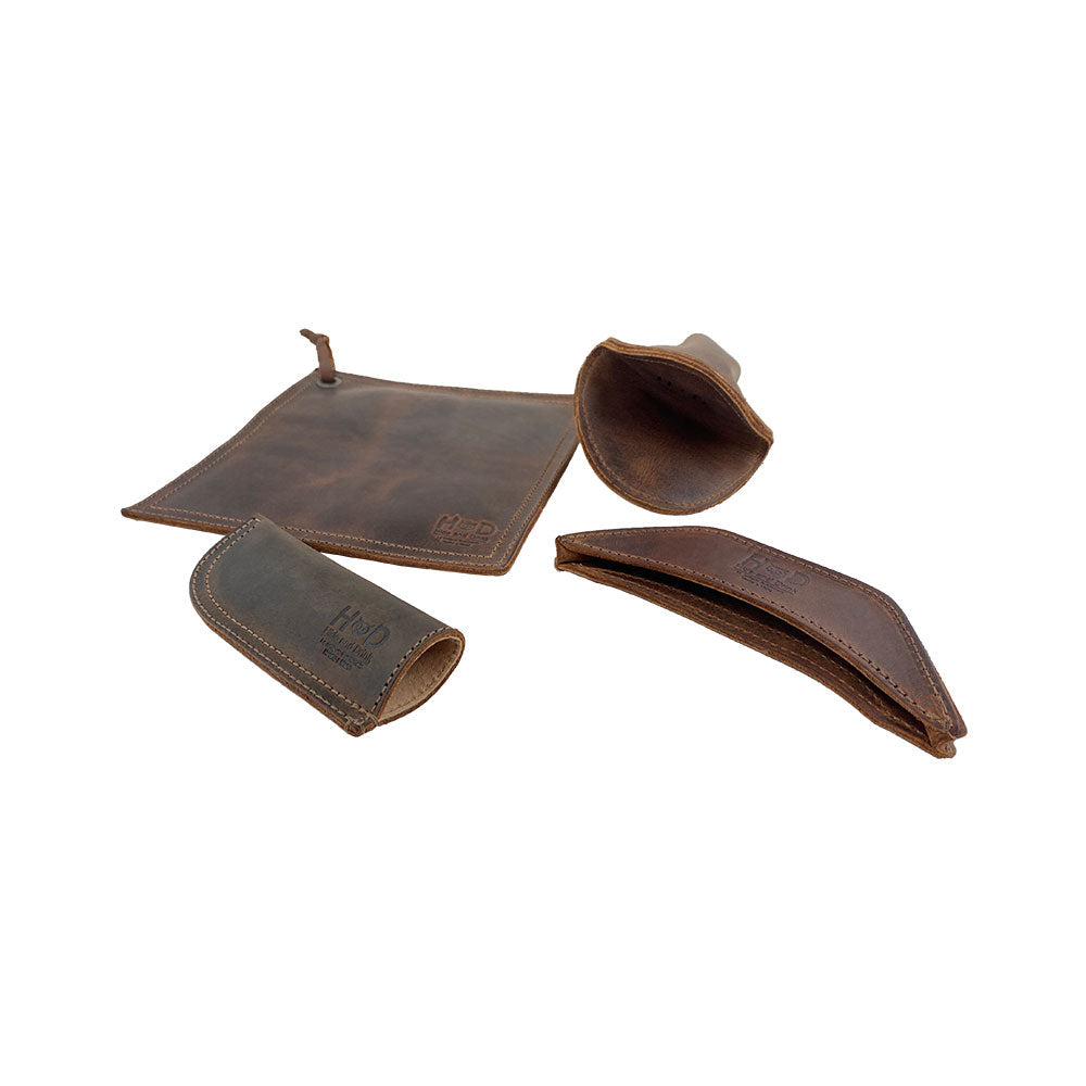 Showcasing Hide & Drink's Hot Handle Holders (Set of 4), this image features a Panhandle, Side Kick, Grip Mitt, and Square Pot Holder constructed from high-quality Full Grain Leather. Hand cut and hand sewn, these artisan pieces are made in small batch production, offering a rustic charm while being practical for cast iron skillets and pans, crafted in La Antigua Guatemala & Oaxaca Mexico.