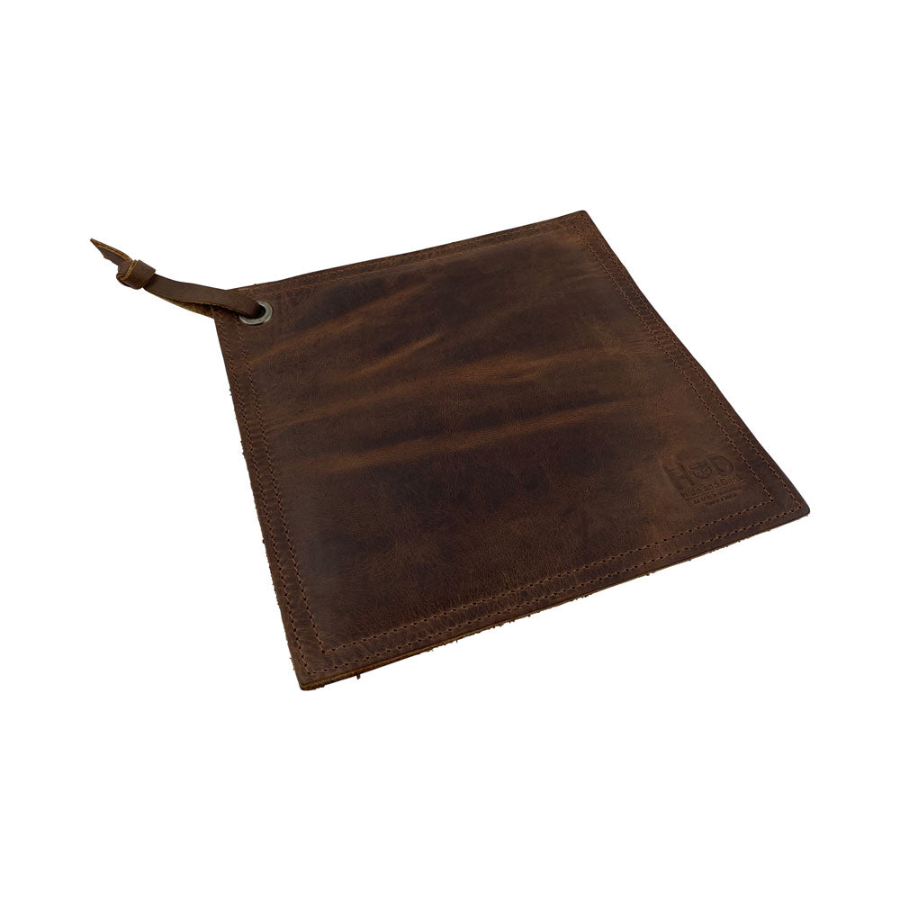 Side view of the Hide & Drink Pot Pad, crafted from rustic brown leather. It showcases a double-layered design perfect for pot protection while cooking. Artisan handmade in La Antigua Guatemala & Oaxaca Mexico.