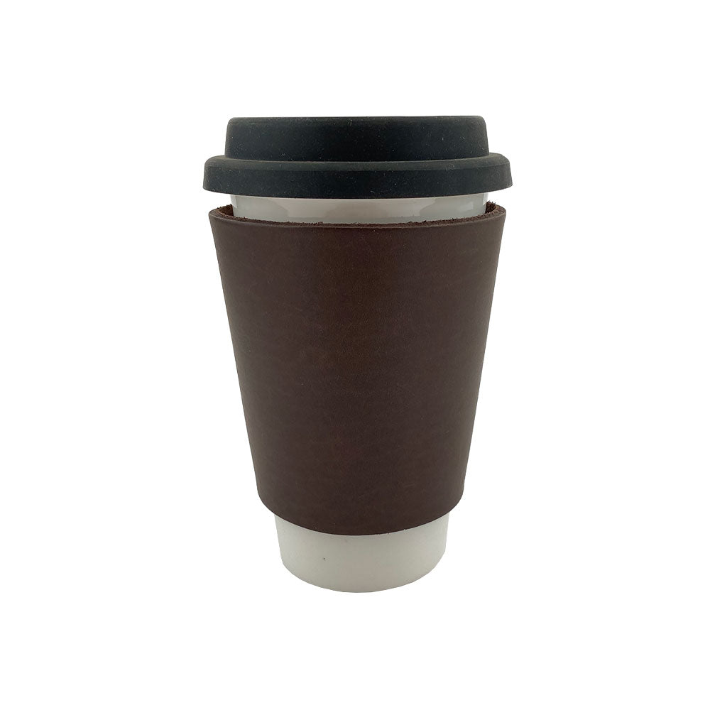 Hide & Drink's leather Pint Sleeve fitted around a ceramic coffee cup, showcasing its perfect blend of functionality and style. This classic piece is designed for temperature control and is adorned with brass metal rivets, embodying small batch artisan craftsmanship from La Antigua Guatemala & Oaxaca Mexico.