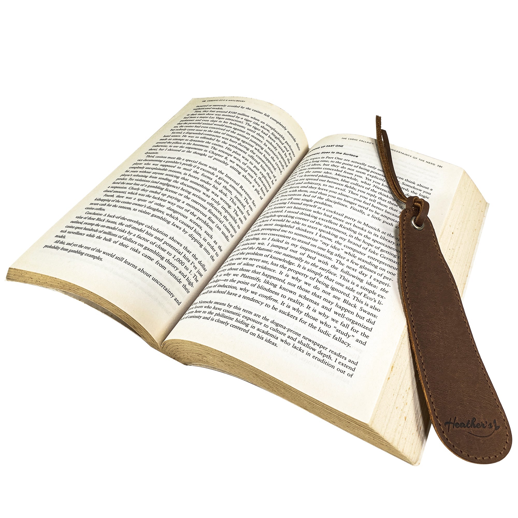 Heather's Bookmark (3 Pack) featuring a full grain leather bookmark placed in an open book, showcasing its unique design. Ideal for literature fans and those seeking a thoughtful gift for book lovers. Bookmark Page Marker (3 Pack) Book Lovers, Page Turners, Travel Readers, Literature Fans, Book Club Gifts, Full Grain Leather, StockyardX, Small Batch Production, Hand Cut, Hand Sewn, Fire Branded, Artisan, Handmade in La Antigua Guatemala & Oaxaca Mexico.