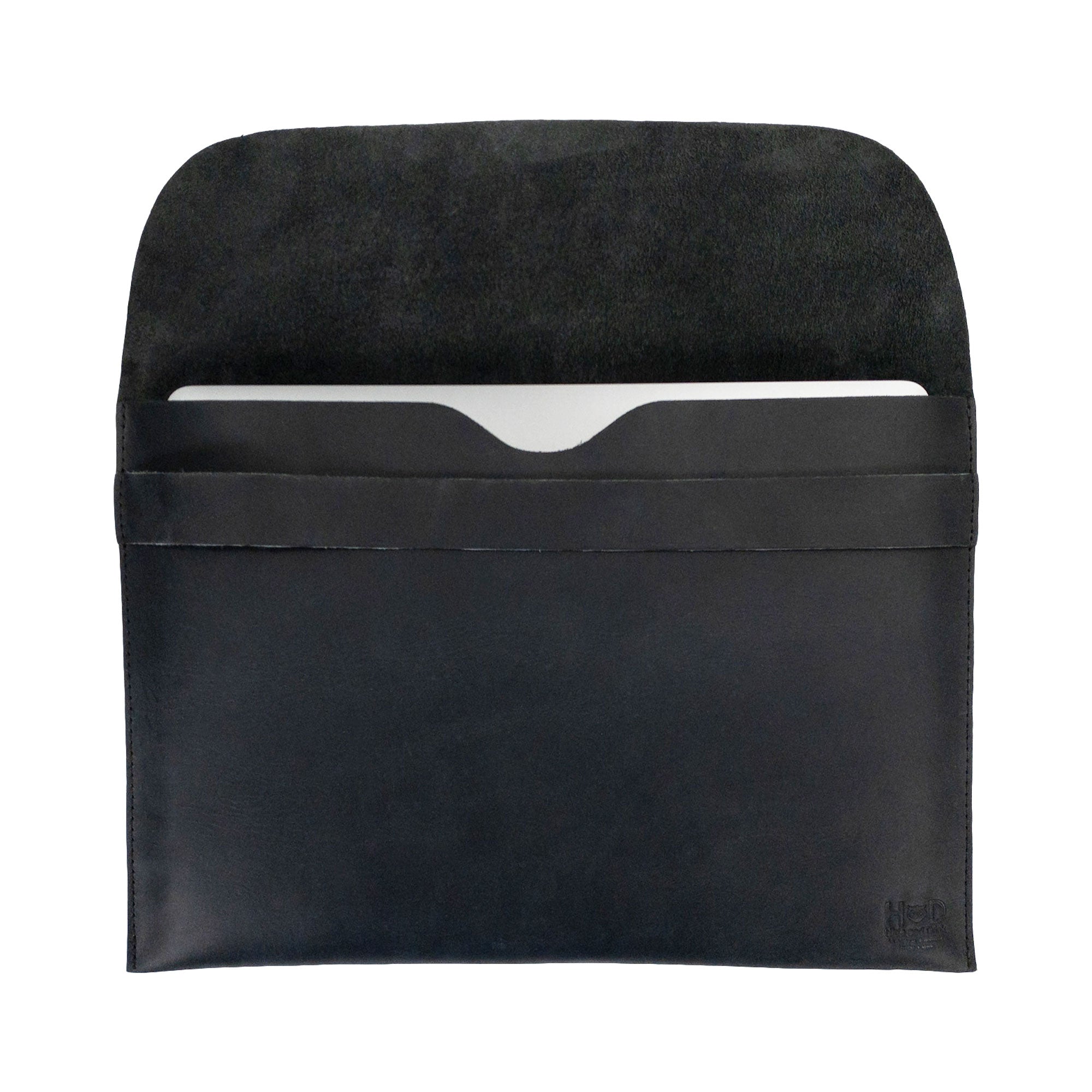 Open view of the black Hide & Drink MacBook Slim Case, accommodating a laptop snugly. It is compatible with MacBook Air/Pro 13 Inch with M1 Chip, showcasing the artisanal work of hand cut and hand sewn details, emphasizing full grain leather quality.
