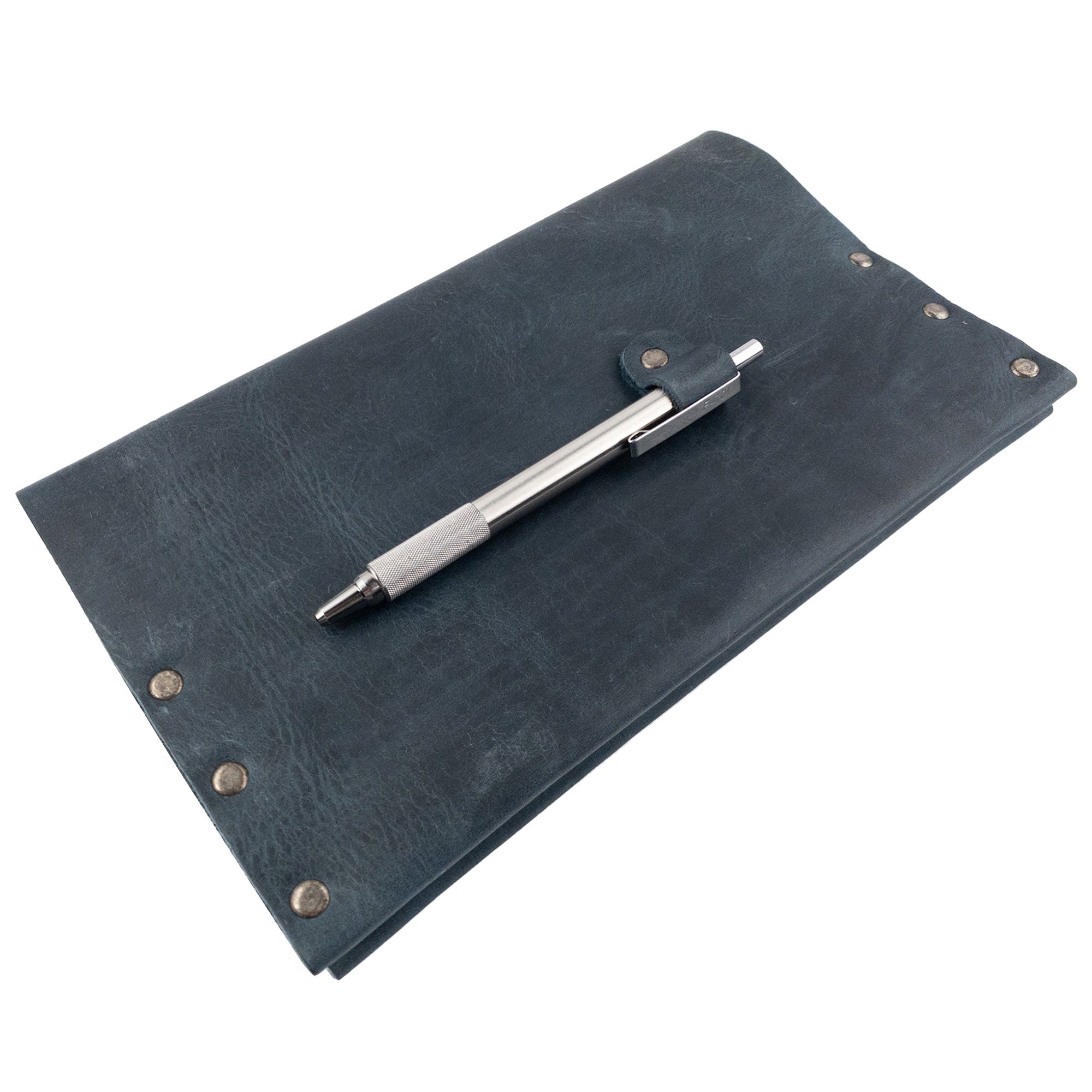Riveted Journal Cover (5 x 8.50 in.) from Hide & Drink displayed with a pen, showcasing its durable full grain leather and classic sleeve style. This handmade item is part of small batch production and embodies artisan craftsmanship made in La Antigua Guatemala & Oaxaca Mexico.