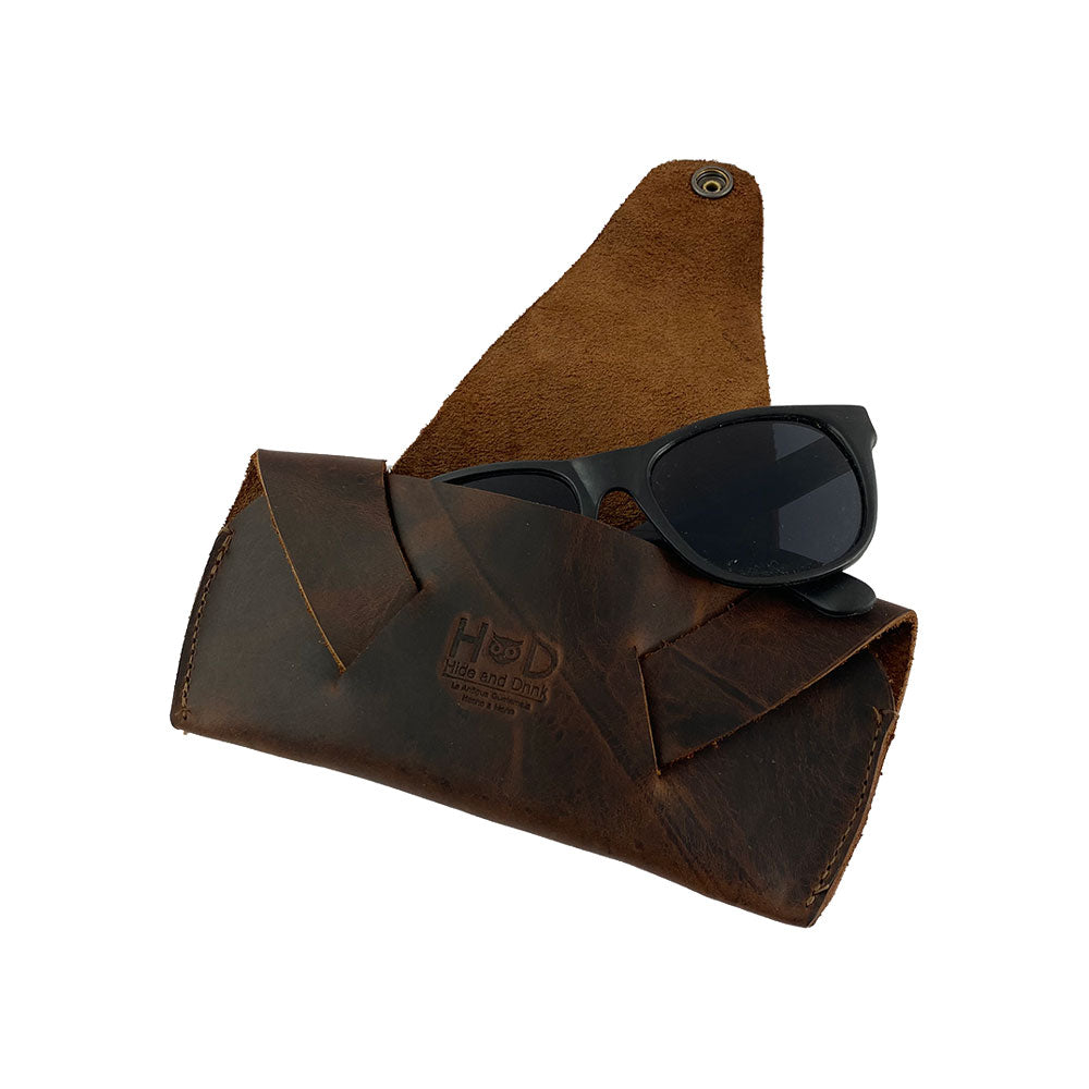 Foldable Sunglass Case by Hide & Drink with sunglasses inside. This Full Grain Leather case offers a stylish and practical solution for eyewear protection while epitomizing artisan craftsmanship through hand cut and sewn details.