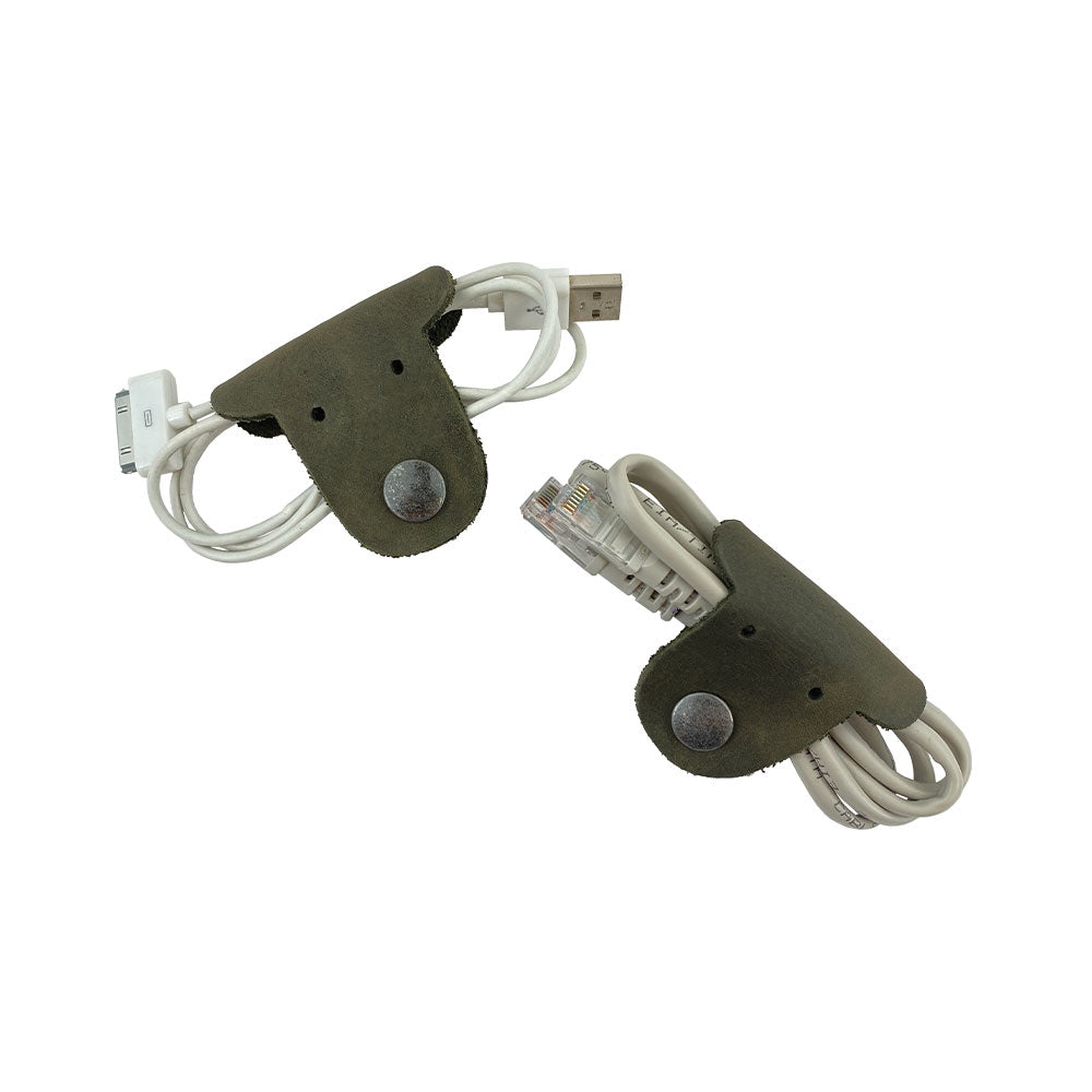 Two green Dog Shaped Cord Keepers neatly organizing USB cables, an innovative design by Hide & Drink made from Full Grain Leather. Dog Shaped Cord Keeper (Cord Clam) 2-Pack, Full Grain Leather, StockyardX, Small Batch Production, Hand Cut, Hand Sewn, Fire Branded, Artisan, Handmade in La Antigua Guatemala & Oaxaca Mexico.