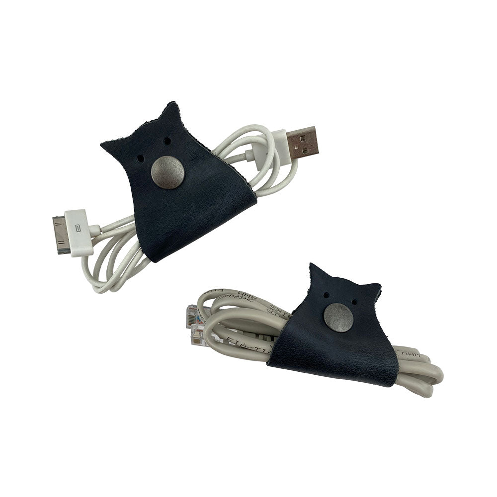 Owl Shaped Cord Keeper (2-Pack) by Hide & Drink displayed with a variety of cords, showcasing its functionality and elegant design. Owl Shaped Cord Keeper (Cord Clam) 2-Pack. Full Grain Leather, StockyardX, Small Batch Production, Hand Cut, Hand Sewn, Fire Branded, Artisan, Handmade in La Antigua Guatemala & Oaxaca Mexico.