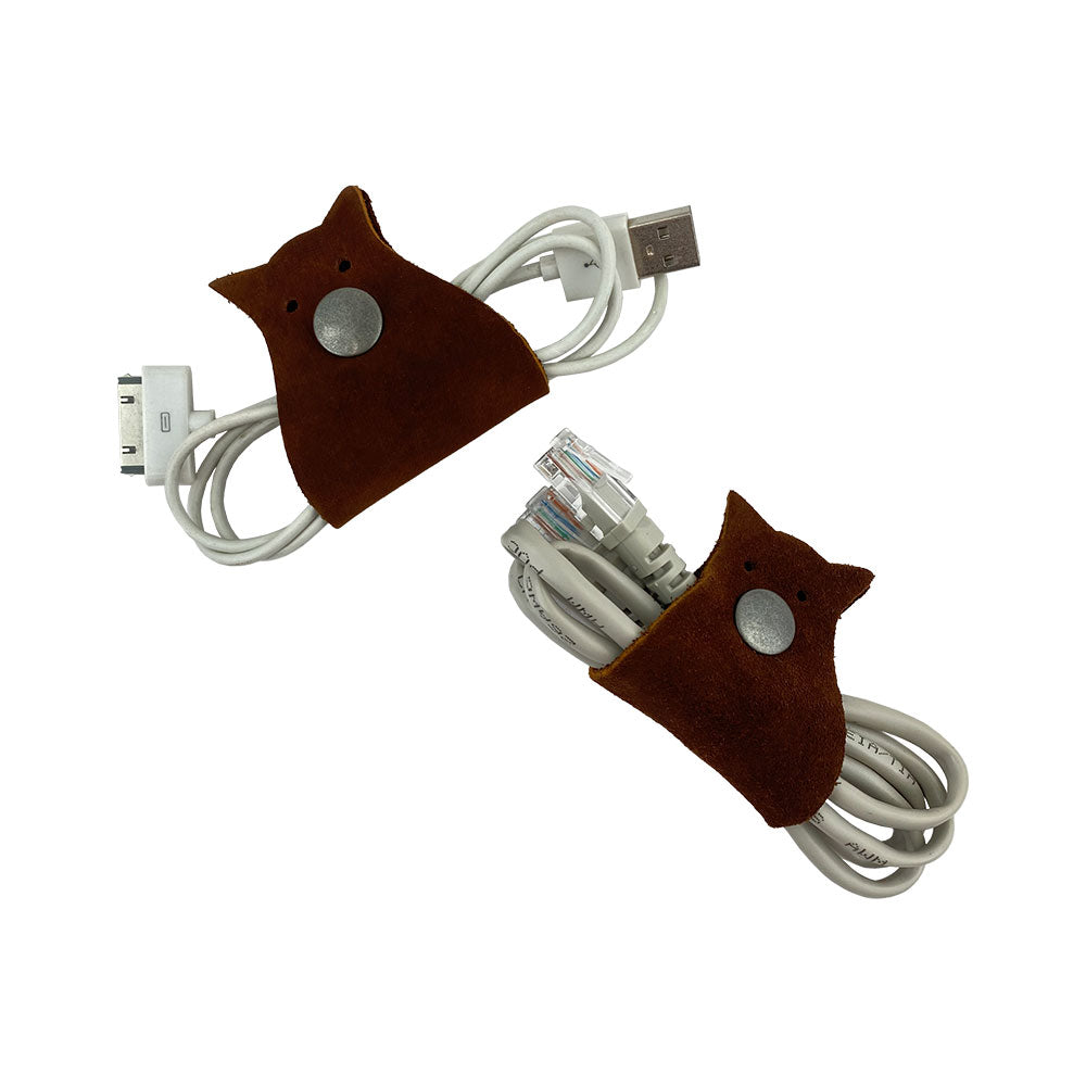 Owl Shaped Cord Keeper (2-Pack) by Hide & Drink displayed with USB and Ethernet cables securely fastened by artfully designed leather holders. Owl Shaped Cord Keeper (Cord Clam) 2-Pack. Full Grain Leather, StockyardX, Small Batch Production, Hand Cut, Hand Sewn, Fire Branded, Artisan, Handmade in La Antigua Guatemala & Oaxaca Mexico.