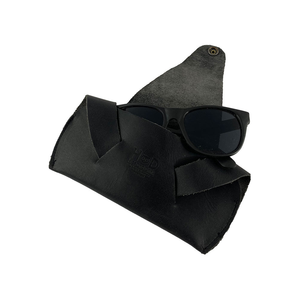 Foldable Sunglass Case by Hide & Drink with sunglasses stored inside, combining style with protection. This case is made from Full Grain Leather, and is a prime example of artisan craftsmanship, featuring hand cut and sewn methods.