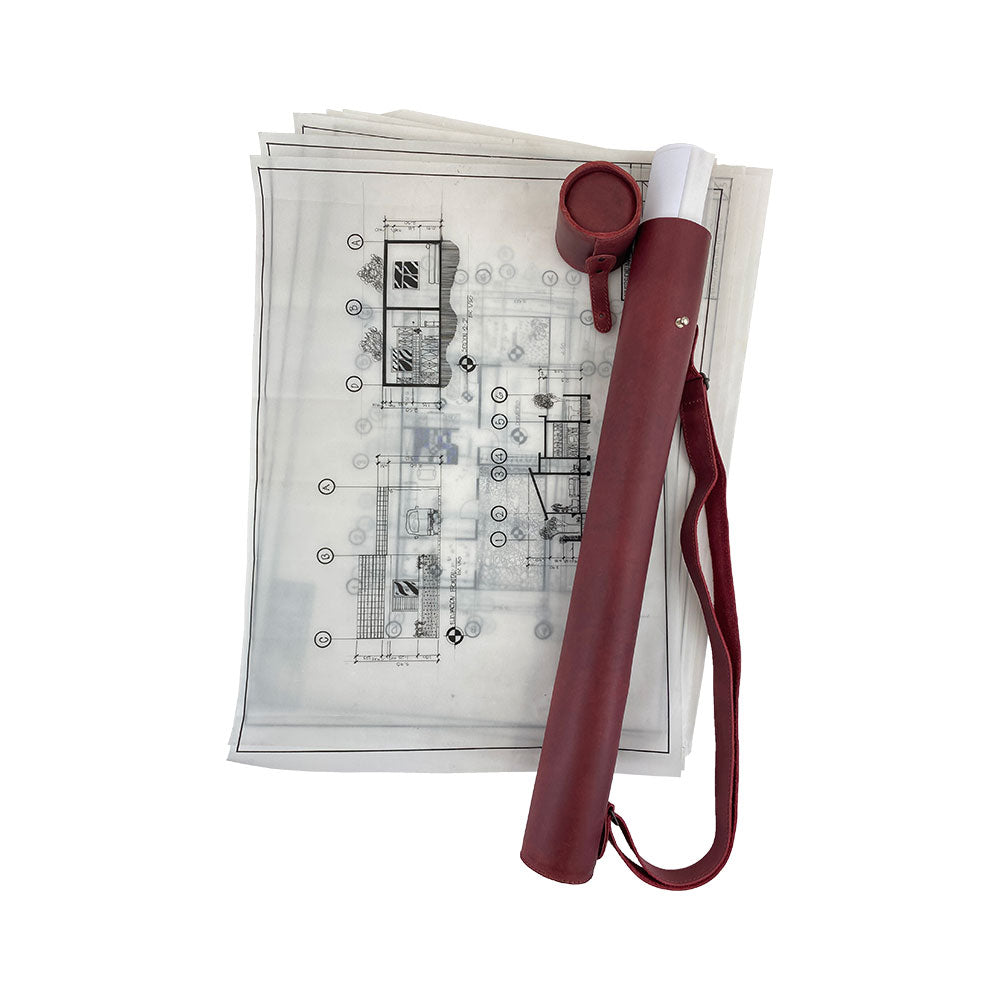 Hide & Drink's Blueprint Tube (A2 Paper Size) alongside rolled documents, showcasing storage efficiency. This full grain leather tube with an adjustable strap represents artisan craftsmanship and small batch production by StockyardX, handmade in La Antigua Guatemala & Oaxaca Mexico.