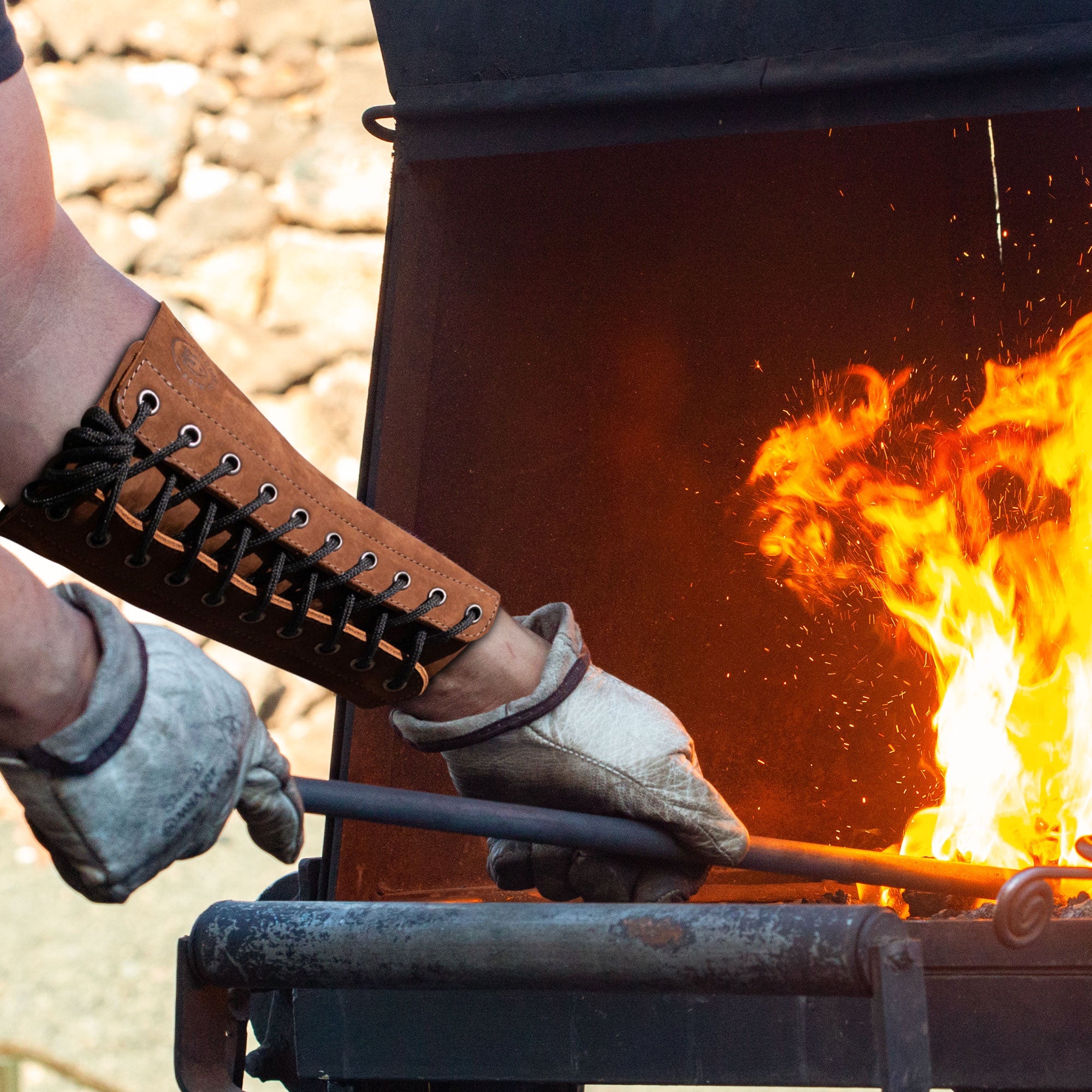The Blacksmith Forearm Protector by Toolshed Hide being used during blacksmithing, highlighting its durability and heat resistance feature. Crafted from full grain leather, this rustic bracer offers protection and is a testament to small batch production and artisan craftsmanship.
