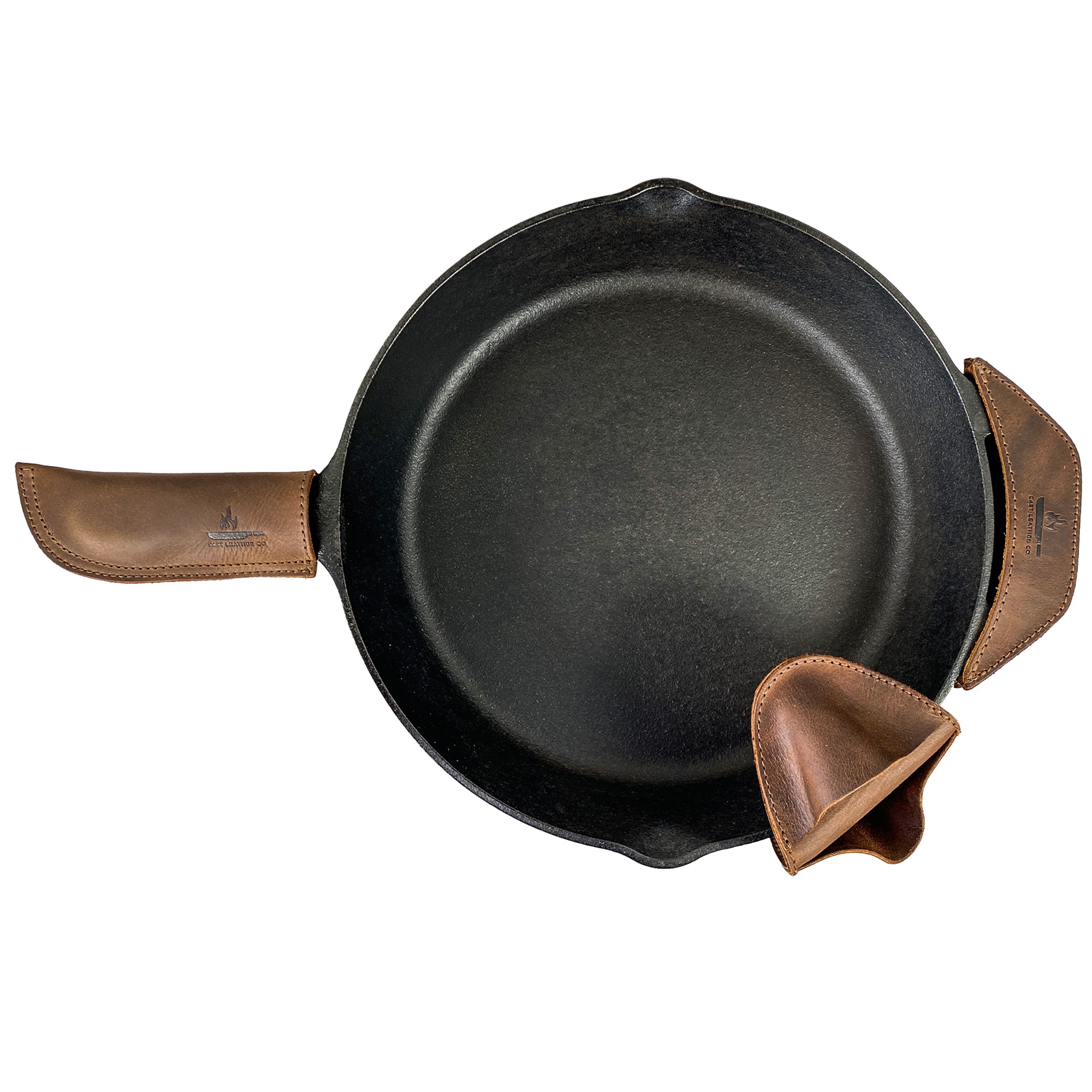This image highlights the Hot Handle Holders Set of 3 by Cast Leather Co., elegantly displaying a cast iron skillet complemented by full grain leather grip holders. Designed as a panhandle, side kick, and grip mitt, they provide reliable assist grips for stately cast iron skillets and pans, showcasing artisan craftsmanship from La Antigua Guatemala & Oaxaca Mexico through small batch production and hand finishing.