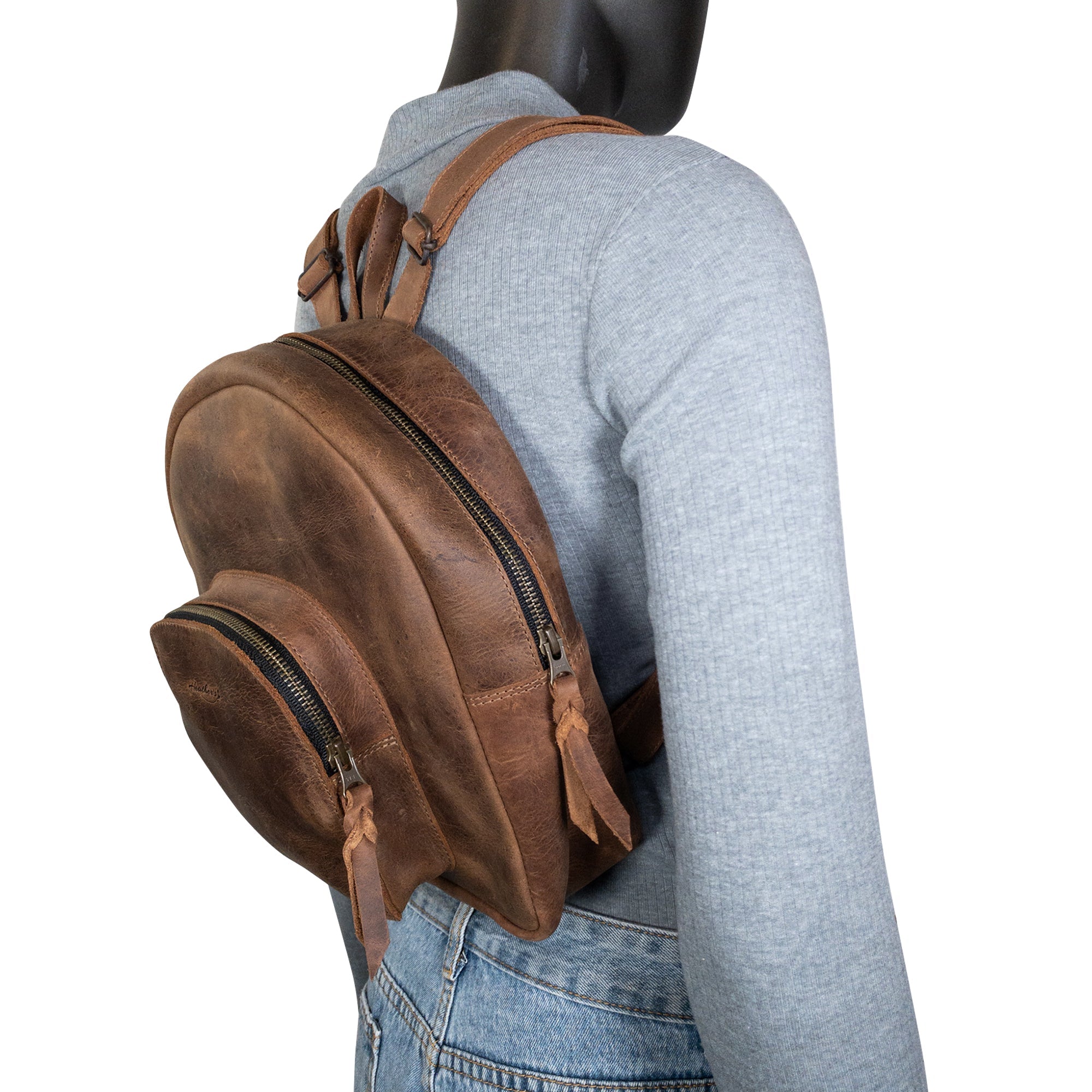 A close-up of Heather's Minimalist Backpack being worn, showcasing its comfortable fit and stylish design. Made from full grain leather, this backpack allows you to carry and organize your essentials like makeup and notebooks with ease, thanks to its adjustable straps. Artisan-crafted in La Antigua Guatemala, emphasizing quality and small batch production.