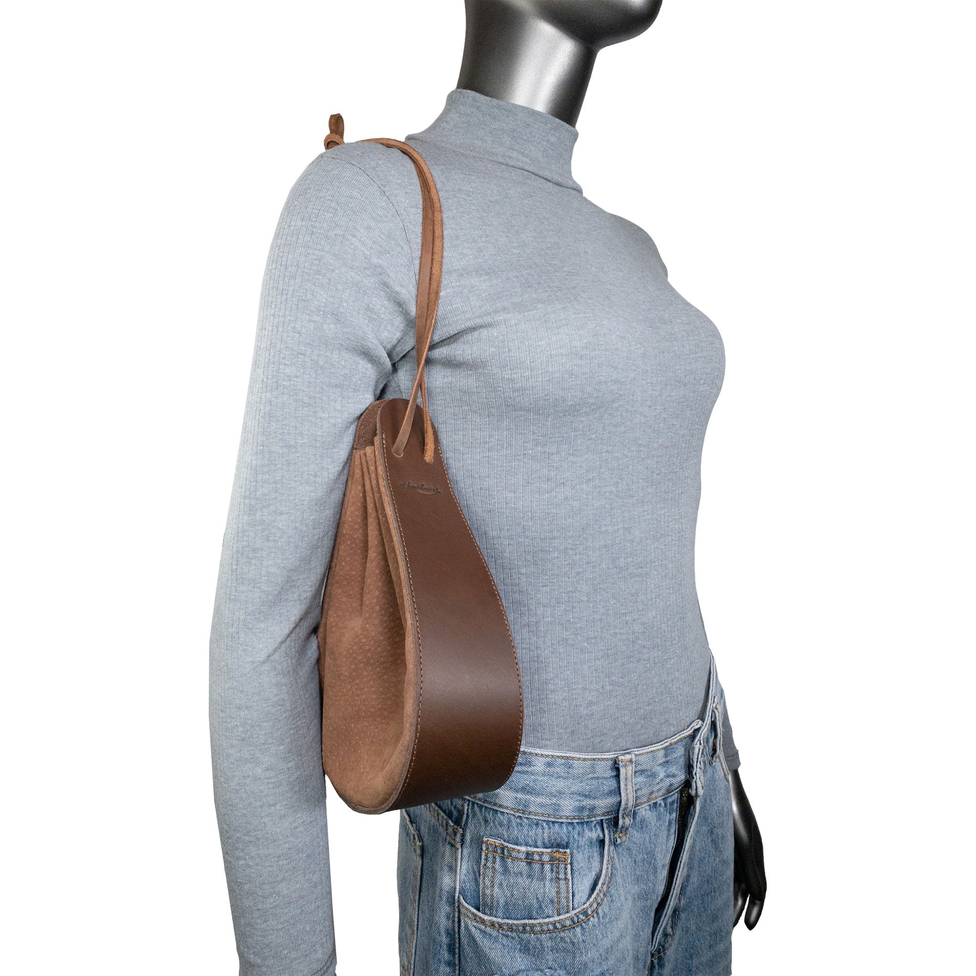 Another angle of Heather's Shoulder Bag displayed on a model, emphasizing its stylish design as a multipurpose rounded shoulder bag. Made from exquisite full grain leather, it's great for travel. The artisan quality is reflected in its small batch production, hand cut and hand sewn attributes, and fire branding, showcasing the craftsmanship in La Antigua Guatemala & Oaxaca Mexico.