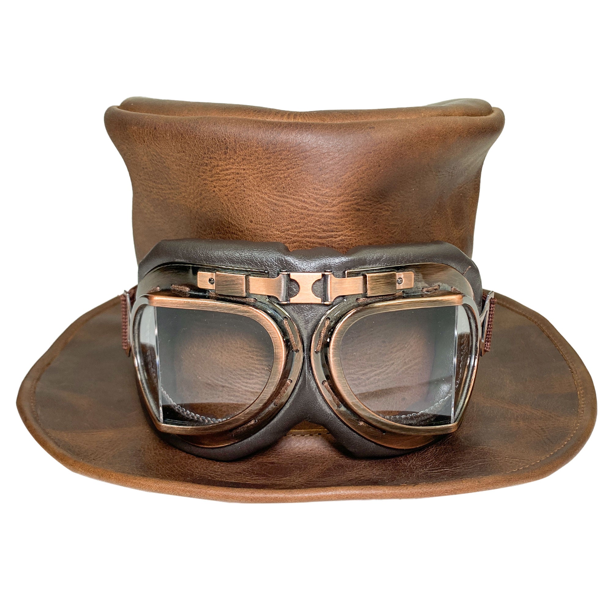 A stunning depiction of the Hide & Play Top Hat adorned with goggles, illustrating its unique steampunk flair. This Top Hat is a fantastic choice for cosplay, Halloween, performances, films, and shows. The Mad Hatter Top Hat is crafted from full grain leather, with small batch production, hand cut, hand sewn artistry, and fire branding by talented artisans in La Antigua Guatemala and Oaxaca Mexico.