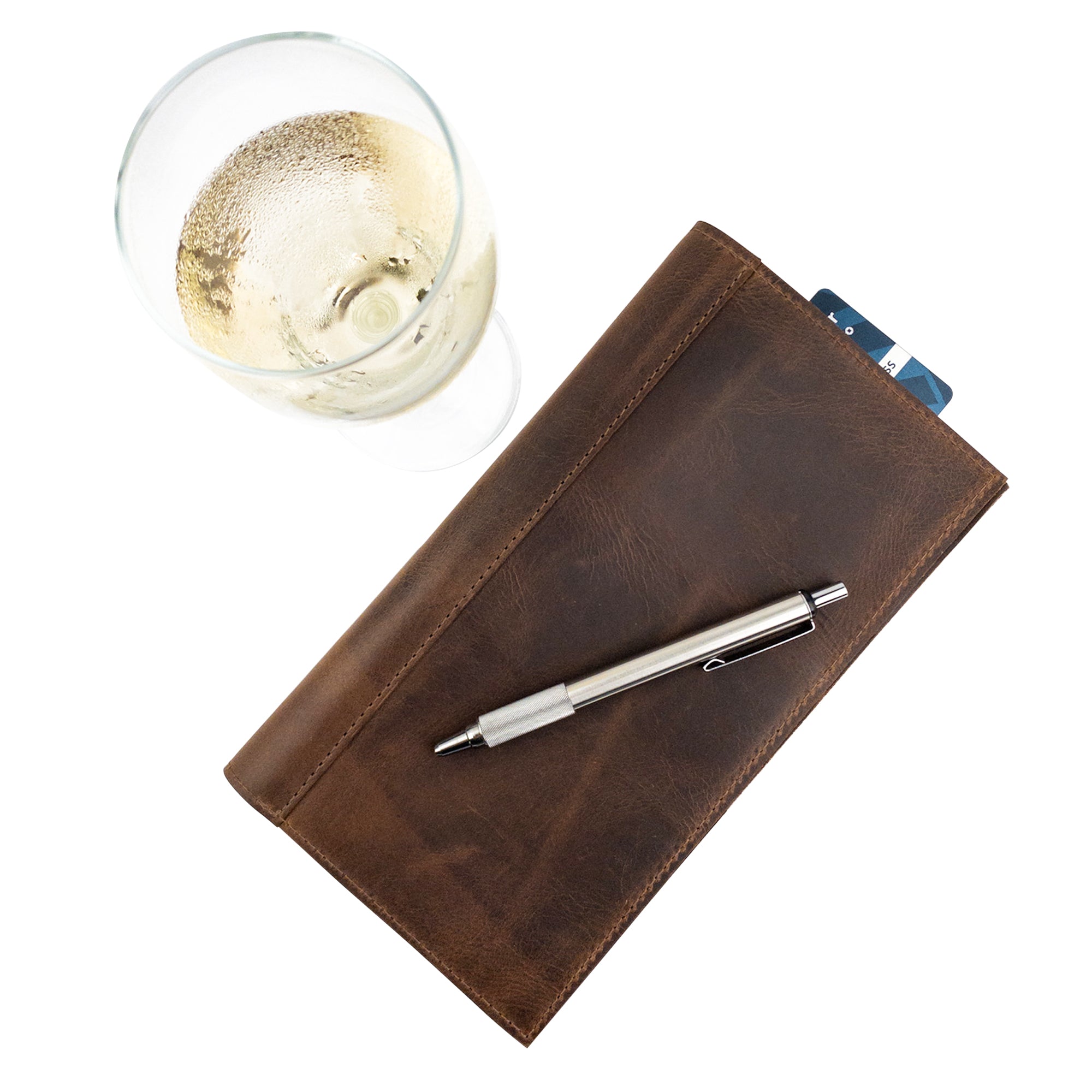 Top view of the Fancy Check Presenter by Hide & Drink, with a sleek Full Grain Leather look and a pen alongside. This handmade item serves as a durable bill holder for waiters and waitresses, exemplifying artisan craftsmanship in restaurant accessories.