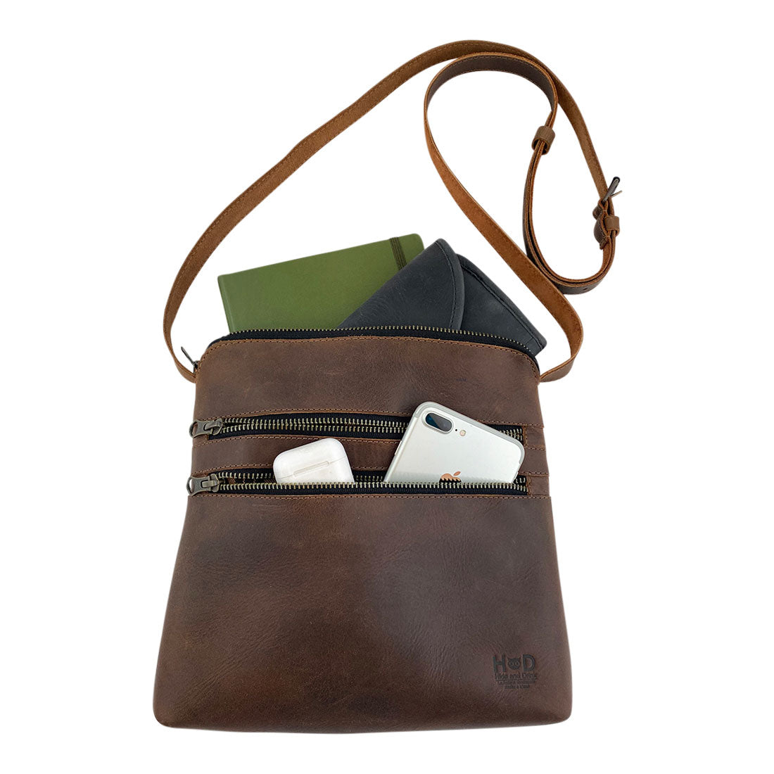Open view of the 3 Zipper Satchel by Hide & Drink, featuring a practical layout with essential items like a notebook and phone nestled inside. This durable handbag is made for everyday adventures. 3 Zipper Satchel - Versatile Handbag, Handmade from Full Grain Leather and Plaid Cotton, Small Batch Production, Hand Cut, Hand Sewn, Fire Branded, Artisan, Handmade in La Antigua Guatemala & Oaxaca Mexico.
