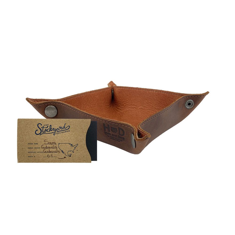The Valet Tray with Sheep Skin by Hide & Drink, featuring a rustic design with an attached business card for scale. This catchall is ideal for storing keys, coins, and other personal items. Crafted from Full Grain Leather & Sheepskin, it represents artisanal quality and comes from small batch production, handmade in La Antigua Guatemala & Oaxaca Mexico.