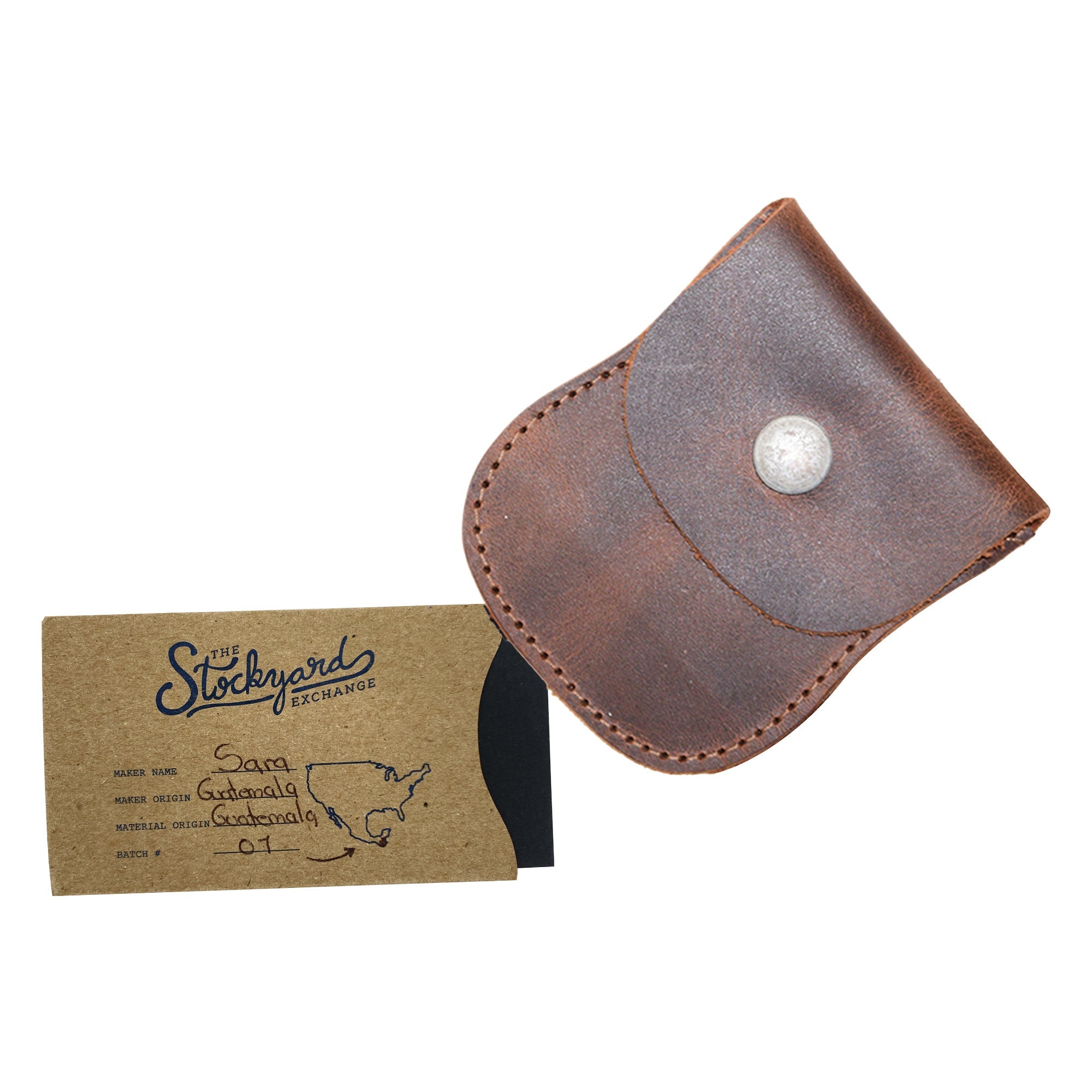 The Curvy Coin Pouch by Hide & Drink next to a business card, highlighting its functional design as a travel accessory made from full grain leather, perfect for organized storage.