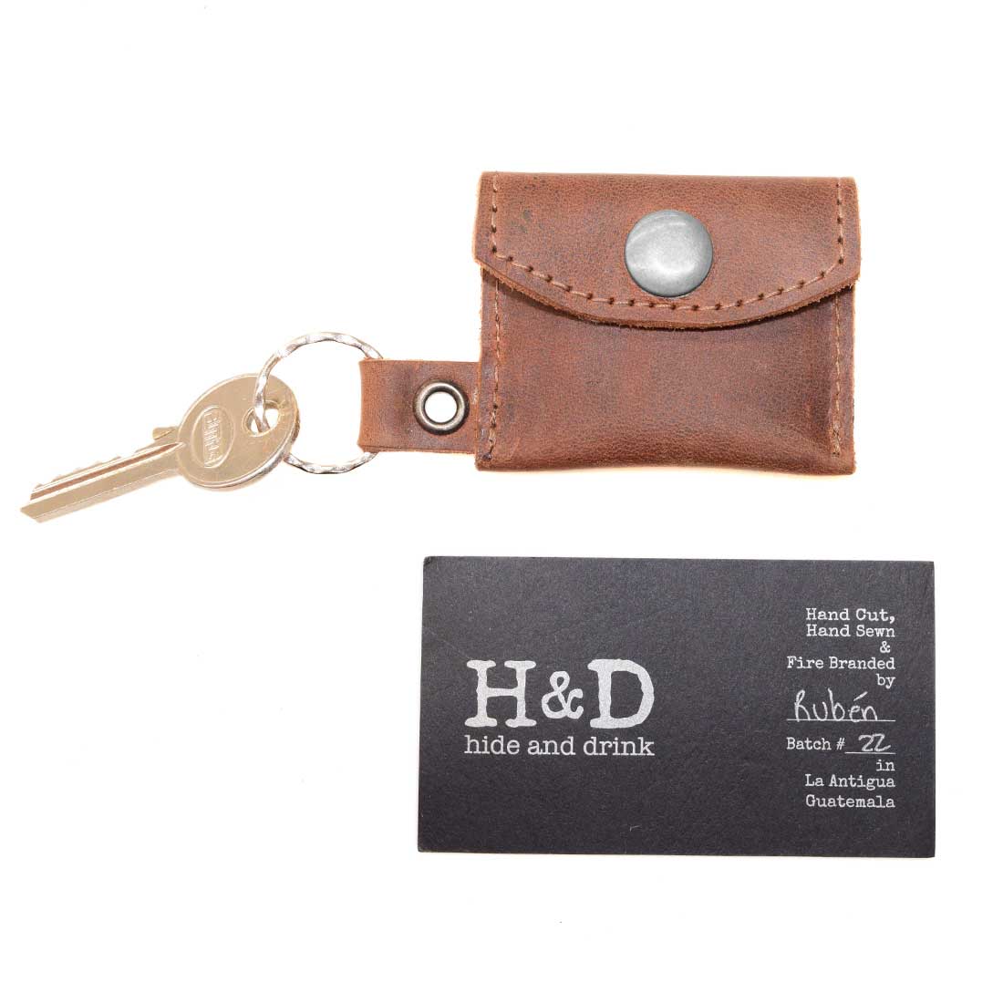 Tiny Coin Holder Keychain by Hide & Drink, paired with keys, emphasizes its craft and utility in using Full Grain Leather. This handmade accessory showcases small batch production techniques and artisan quality from La Antigua Guatemala.