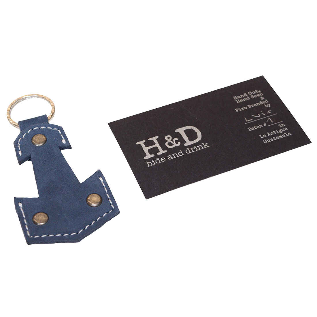 Anchor Keychain by Hide & Drink next to a business card, emphasizing its artisan quality. This handmade keyring, crafted from Full Grain Leather, is perfect for sailors and travelers, embodying small batch production and artisan skills from La Antigua Guatemala & Oaxaca Mexico.