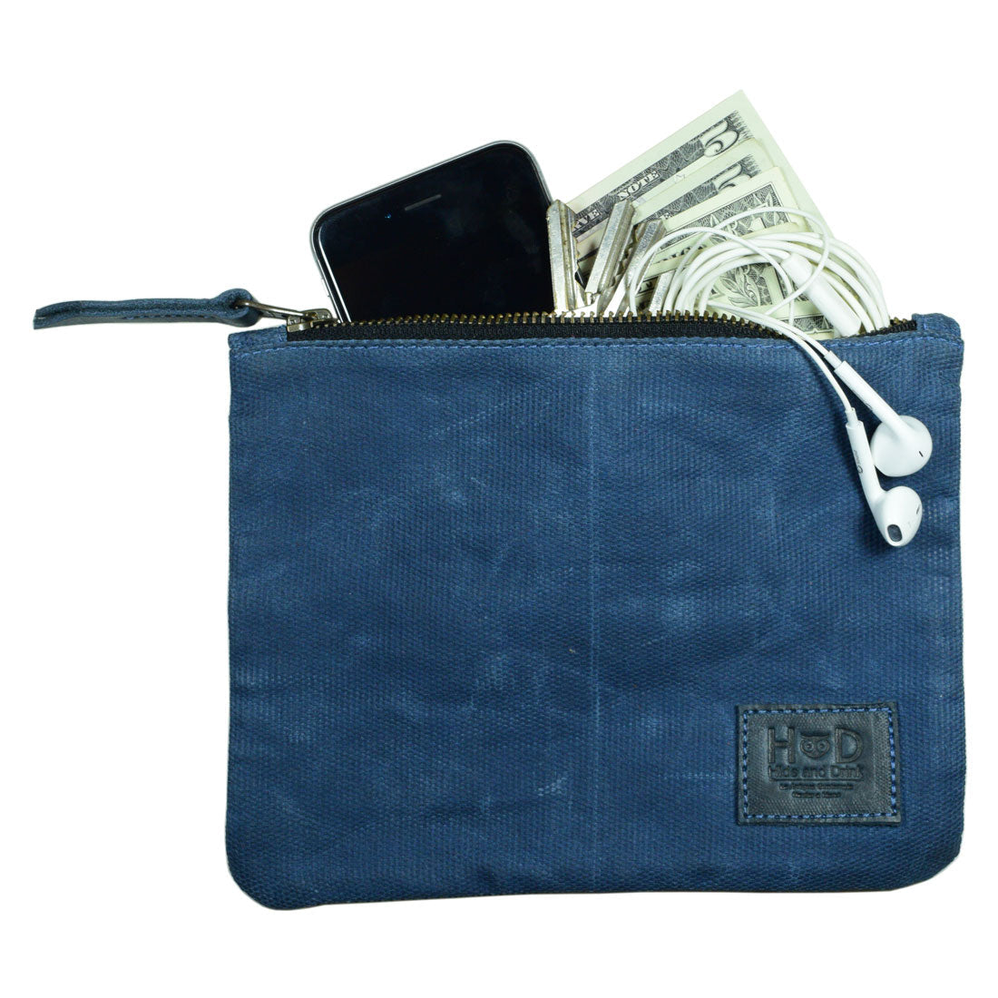 A blue Waxed Zippered Pouch by Hide & Drink, filled with a phone, cash, and earbuds, exemplifying its multi-functional use. This Canvas Zippered Pouch is a lightweight case crafted in Oaxaca Mexico, combining waxed canvas and full grain leather.
