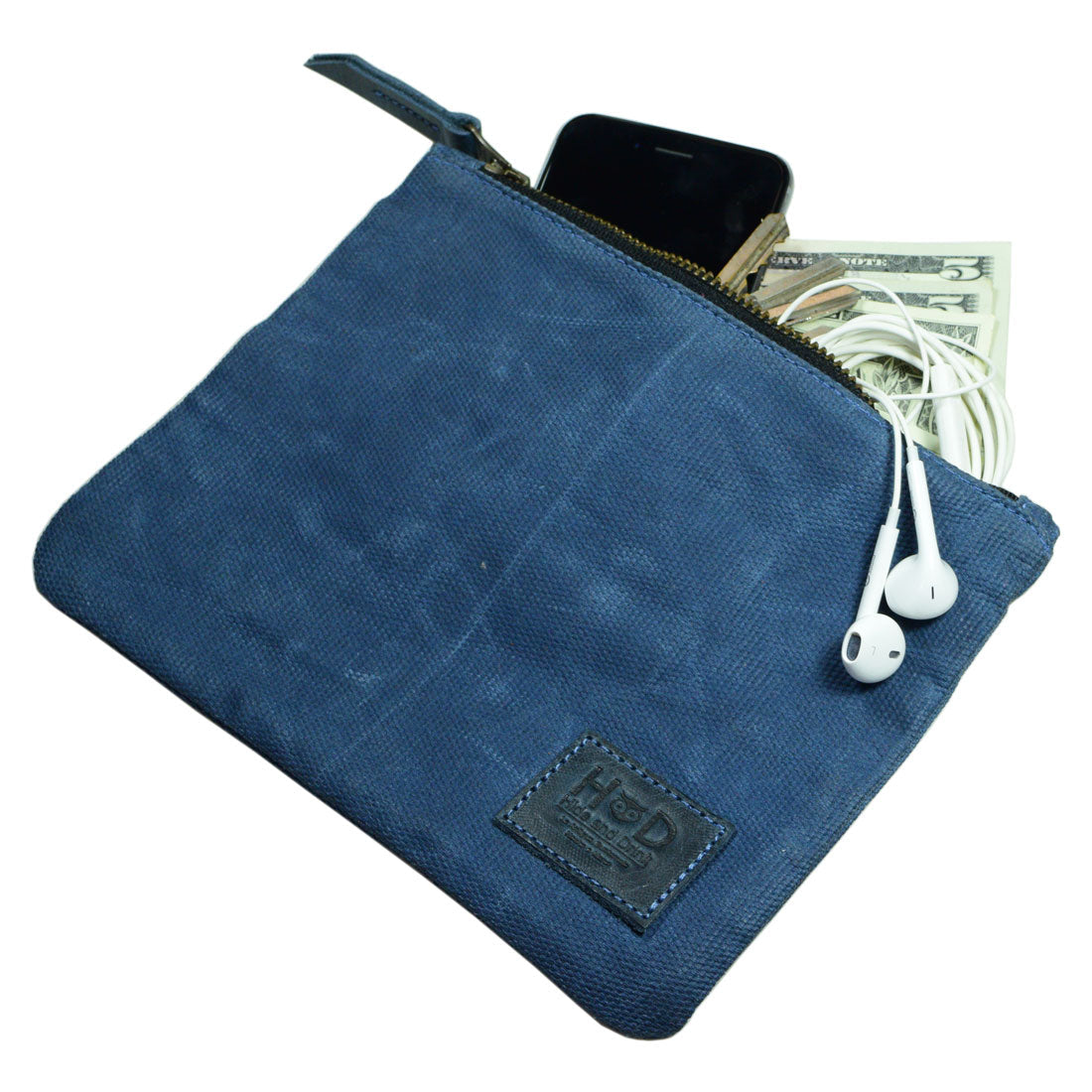 A Waxed Zippered Pouch from Hide & Drink, filled with essentials like cash and earbuds, demonstrating its practical utility. This artisan-made Canvas Zippered Pouch is crafted from waxed canvas and full grain leather in La Antigua Guatemala.