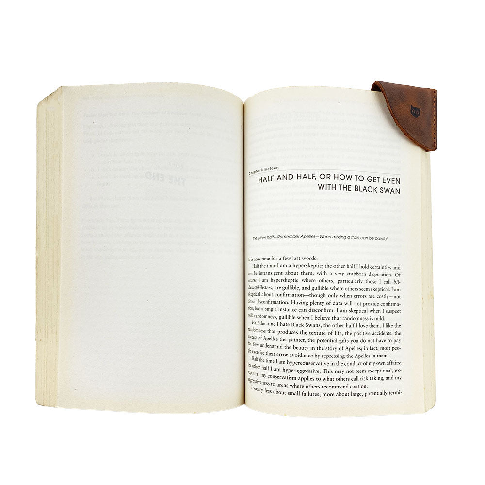 Full grain leather corner bookmark from Hide & Drink, part of the Corner Bookmark 3-Pack, elegantly placed in an open book. This stylish book accessory reflects small batch production, hand cut, hand sewn, and fire branded, highlighting artisan quality from La Antigua Guatemala & Oaxaca Mexico.