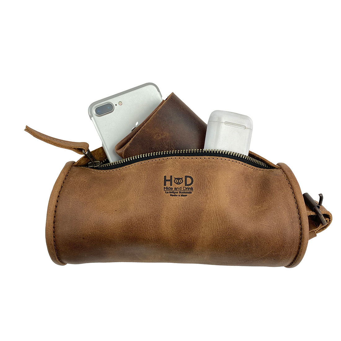 Hide & Drink Bike Bag held with essentials, demonstrating its functionality as a full grain leather cylinder tube pouch. This bicycle accessory reflects artisan craftsmanship with small batch production, handcrafted in La Antigua Guatemala & Oaxaca Mexico.