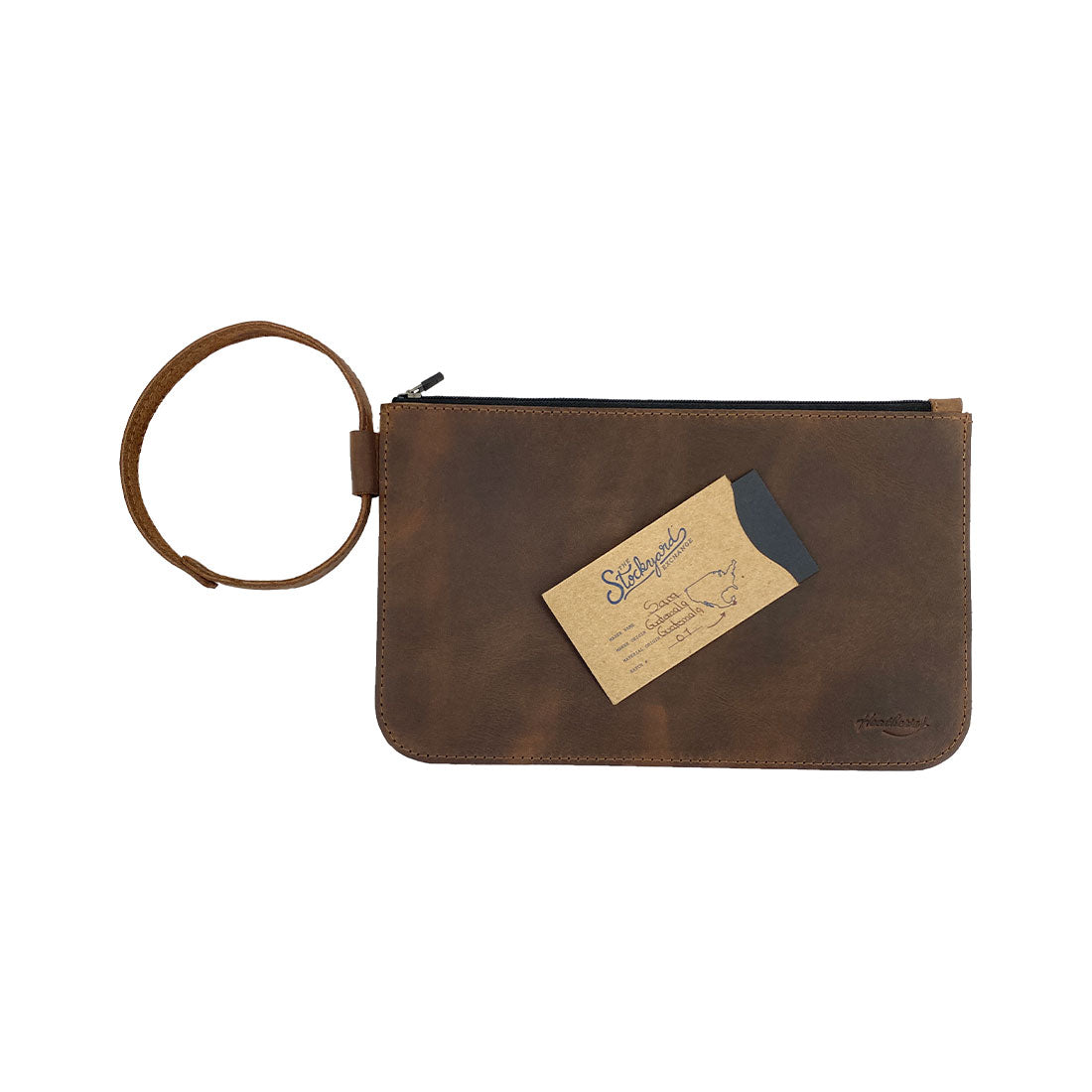 Heather's Rustic Clutch Bag with a business card for size reference, illustrating its practical use as an accessories pouch. Ideal for storing small valuables like makeup and toiletries, this handmade pouch is crafted from high-quality full grain leather. The item showcases artisan craftsmanship through hand cut and hand sewn techniques, featuring fire branded details, made in La Antigua Guatemala & Oaxaca Mexico.