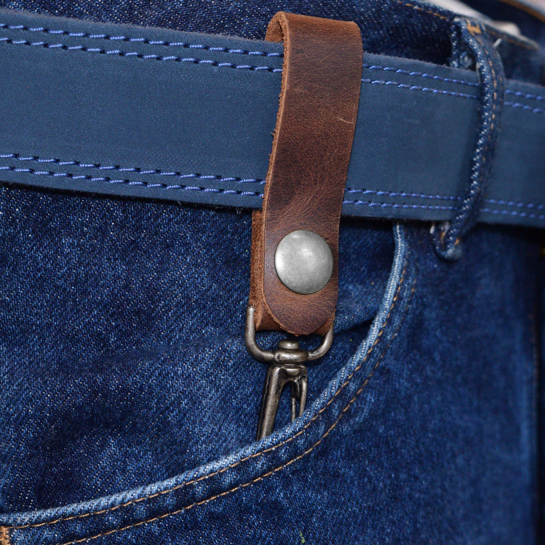 Belt Key Holder by Hide & Drink worn on a belt, showcasing its practical design and rustic charm. Dimensions Length: 4.25 in. Height: 1 in. Width: 0.50 in. Crafted from Full Grain Leather, it ages beautifully and can be protected with mineral oil or beeswax leather conditioner.