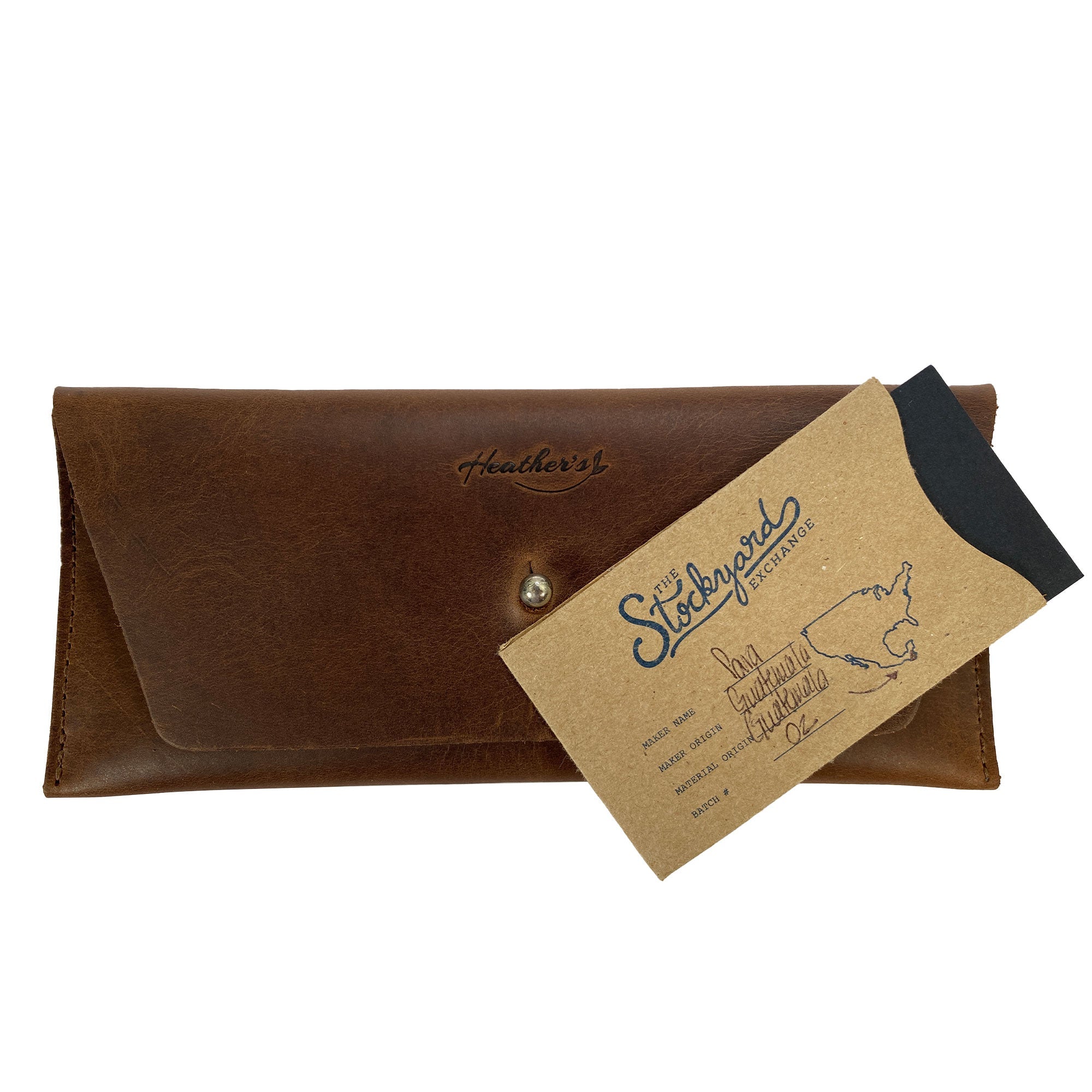 Heather's Long Utility Pouch presented alongside a StockyardX card. This stylish wallet, crafted for carrying and storing cash, coins, and cards, features a vintage, minimalist design made from full grain leather. Hand cut, hand sewn, and fire branded, this artisan piece showcases the quality of small batch production from La Antigua Guatemala.