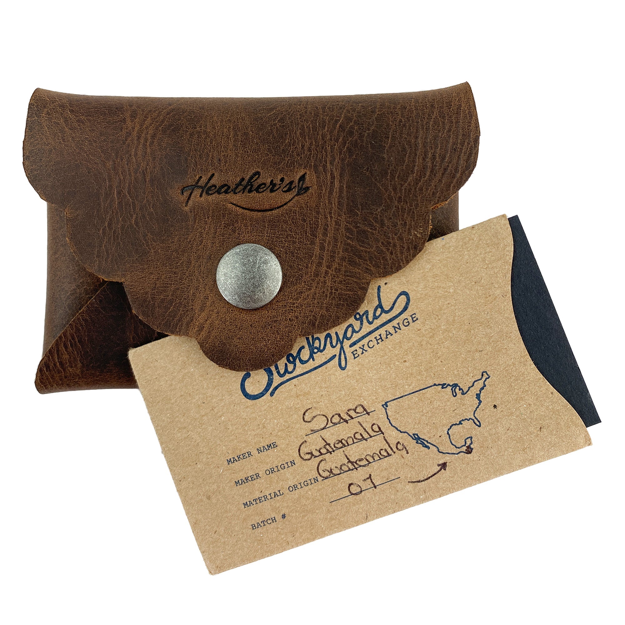 Stylish Envelope by Heather's displayed with its artisan tag describing the craftsmanship and origin. This classy organizer offers compact storage for debit and credit cards, made from full grain leather, showcasing small batch production methods, hand cutting, hand sewing, and fire branding, handmade in La Antigua Guatemala & Oaxaca Mexico.