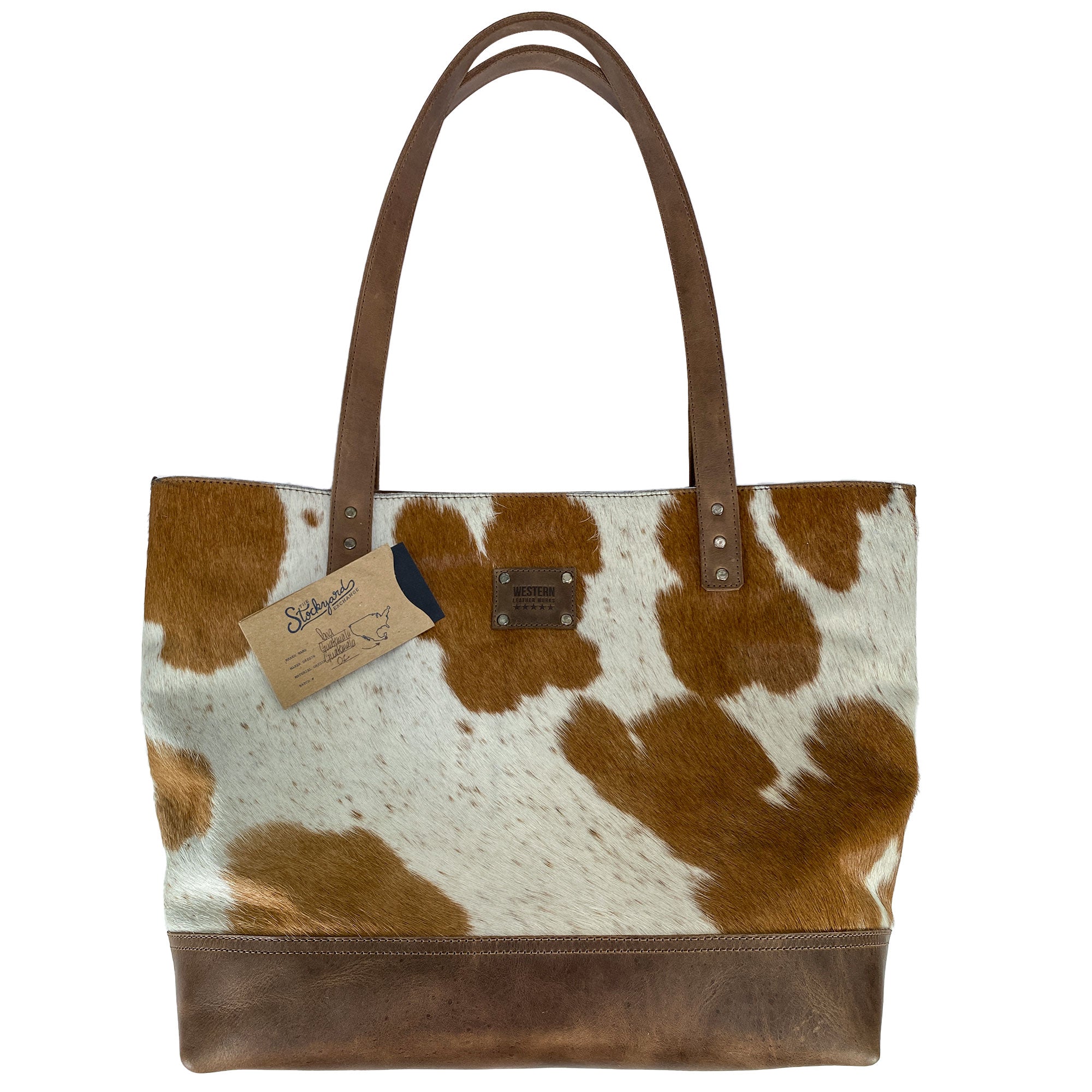 Western Leather Works Formal Tote Bag featuring hang tags as an additional detail on its exterior. This stunning Hair on Hide Full Grain Leather bag carries a rustic charm and is spacious enough for daily needs. Handmade with a plaid cotton interior lining. Artisan, handmade in La Antigua Guatemala & Oaxaca Mexico.
