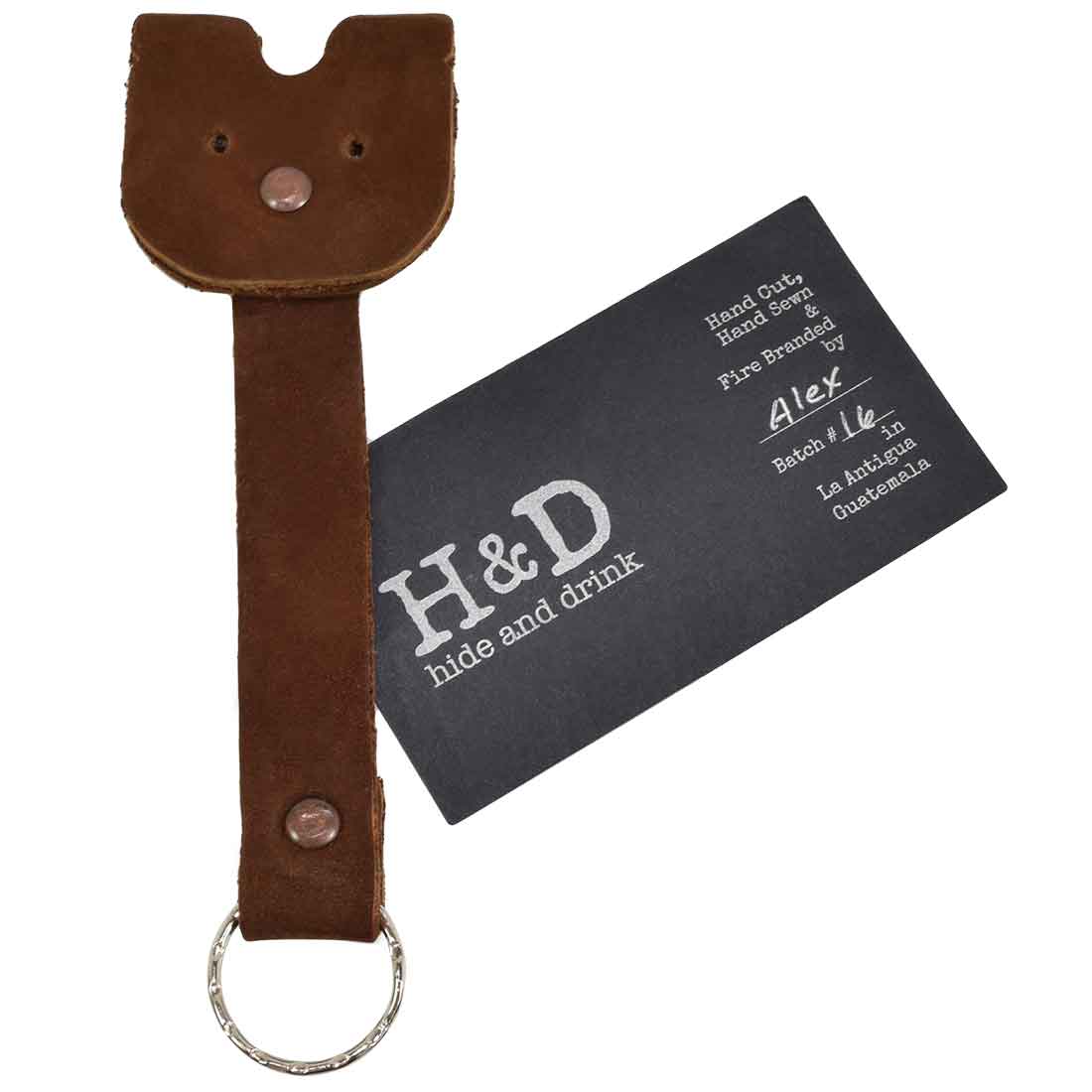 Doggy Fob by Hide & Drink, showcasing a brown Full Grain Leather Critter Keychain with a card showcasing its artisan craftsmanship, ideal for gifting. Critter Keychain Dog Key Ring Pet Fob, Full Grain Leather, StockyardX, Small Batch Production, Hand Cut, Hand Sewn, Fire Branded, Artisan, Handmade in La Antigua Guatemala & Oaxaca Mexico.